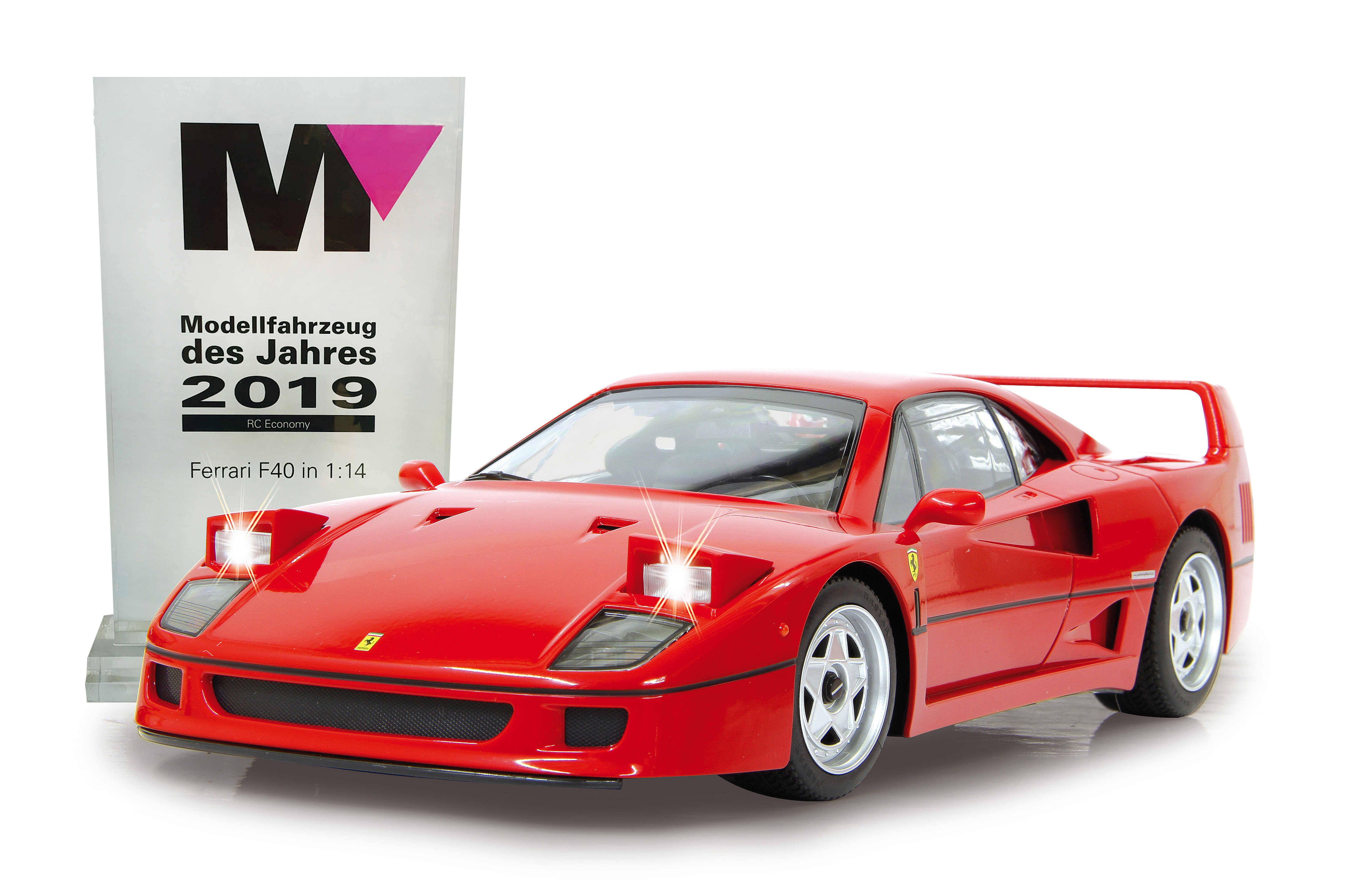 Ein rotes Ferrari F40 Modellauto von 2019 mit leuchtenden Scheinwerfern neben einer Trophäe.
