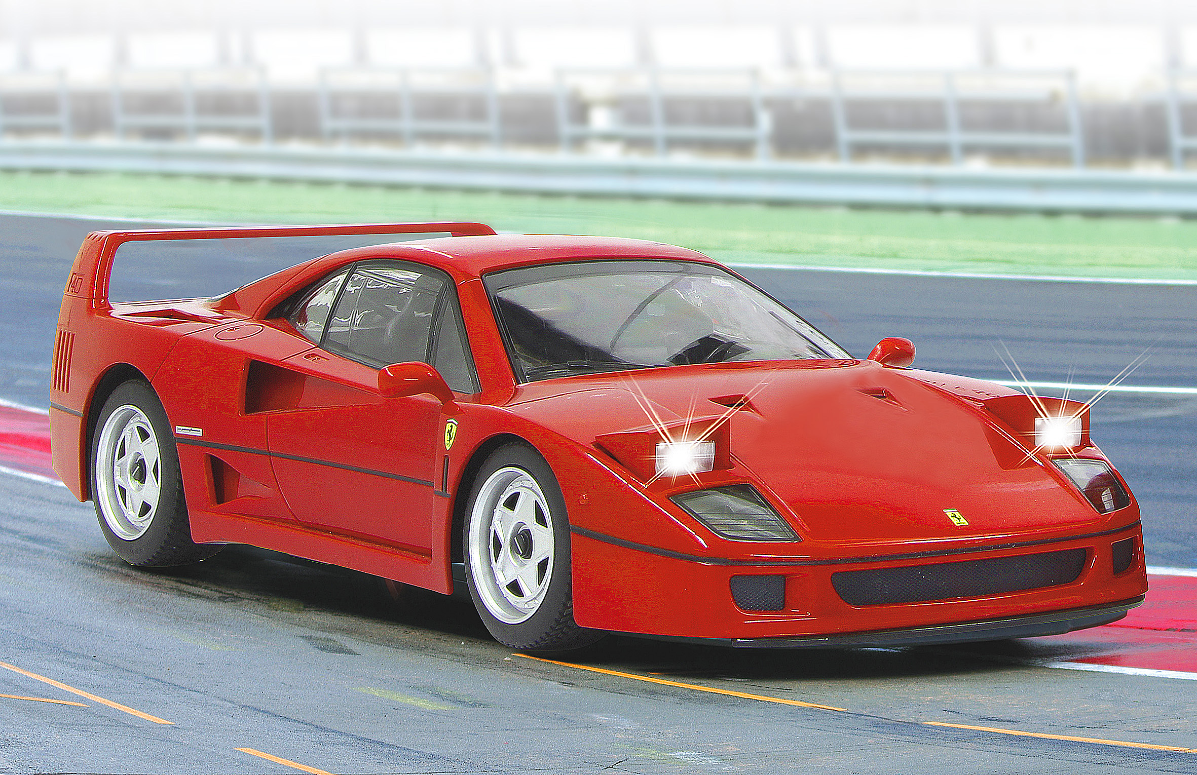 Ein roter Ferrari F40 auf einer Rennstrecke mit Lichtern an.