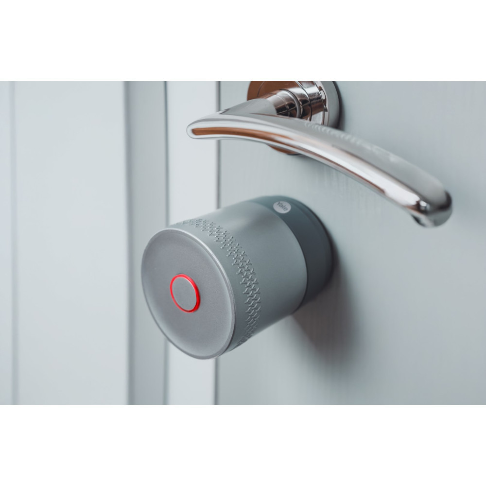 Ein Yale Smart Lock ist an einem silbernen Türgriff an einer weißen Tür befestigt.