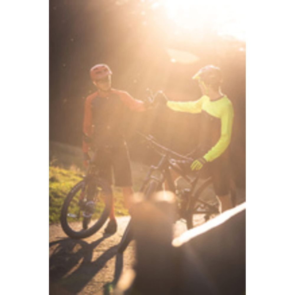 Zwei Radfahrer geben sich die Hand vor Sonnenlicht und Fahrrädern.