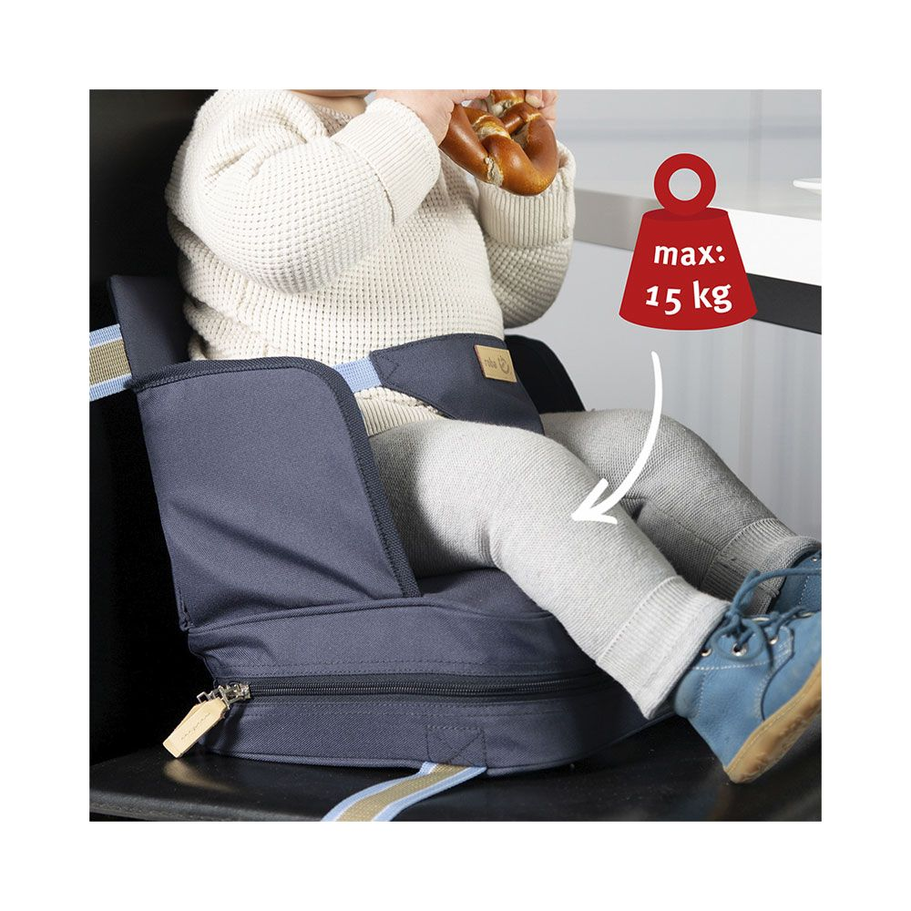 Baby in einem dunklen Hochstuhl-Sitz-Booster, isst eine Brezel. Max. 15 kg.