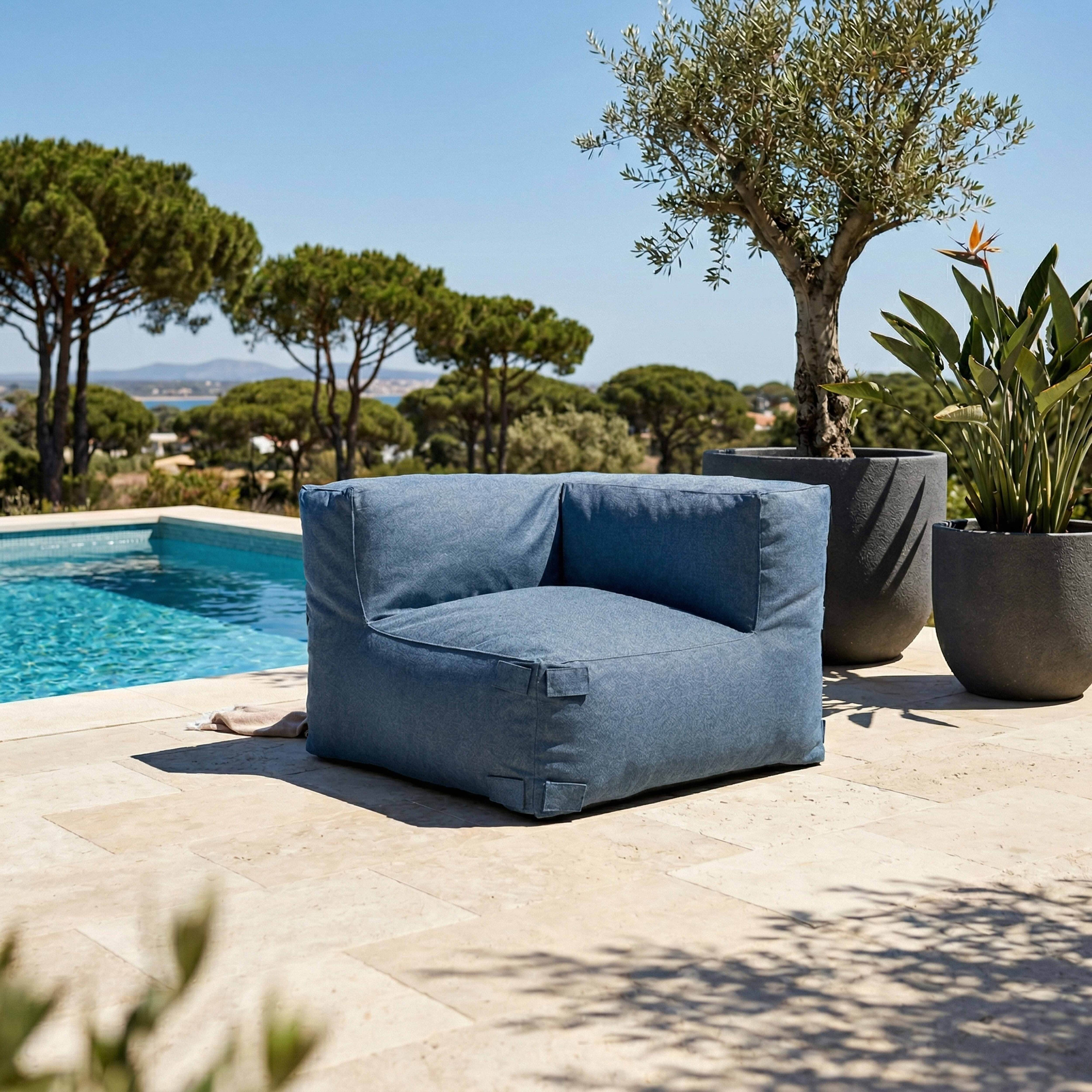 Blauer Sitzsack neben Pool mit Bäumen und Meer im Hintergrund.