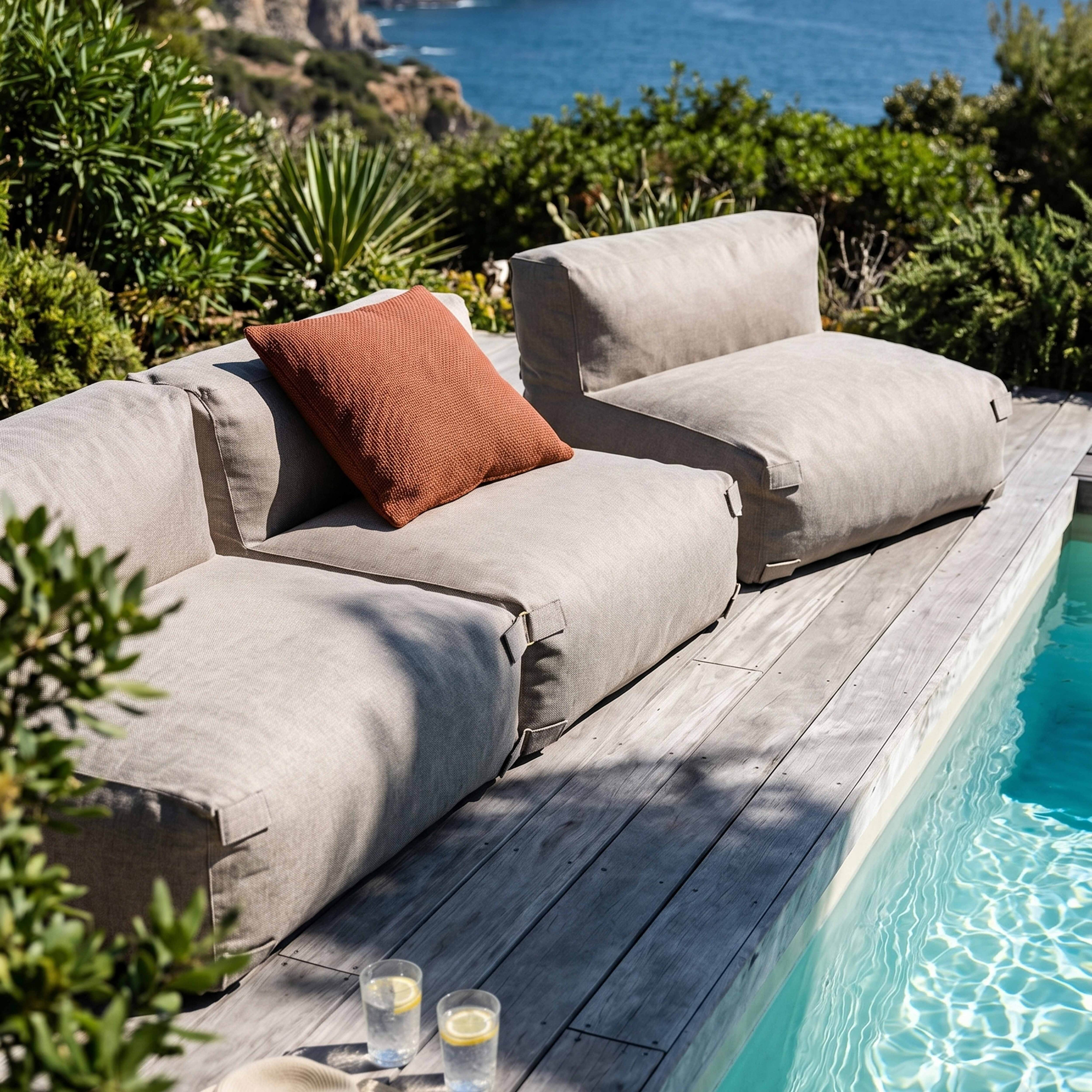 Moderne Lounge-Möbel am Pool mit Blick aufs Meer und üppiger Vegetation.