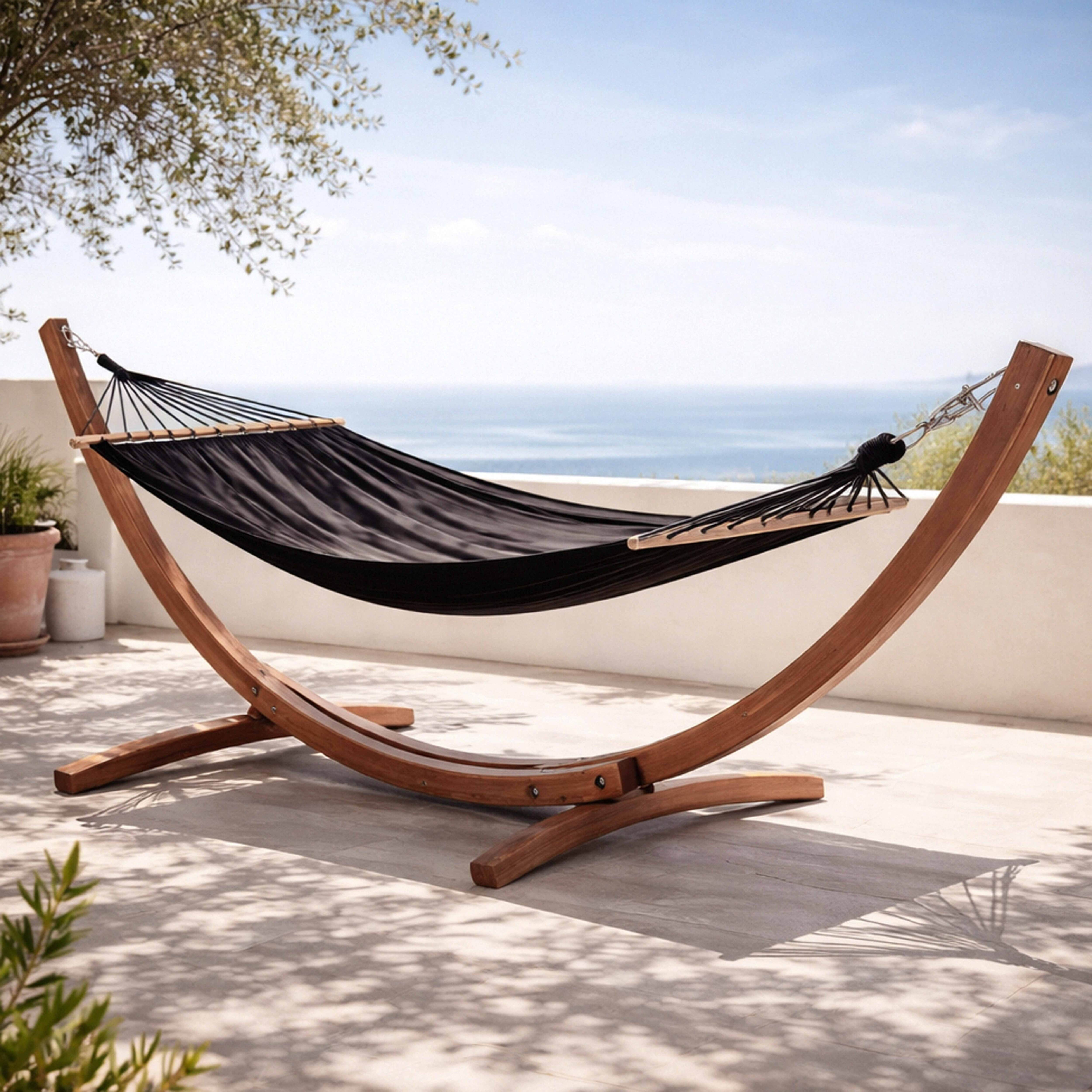 Ein schwarzes Hängematten-Set aus Stoff und Holz steht im Freien mit Blick auf das Meer.