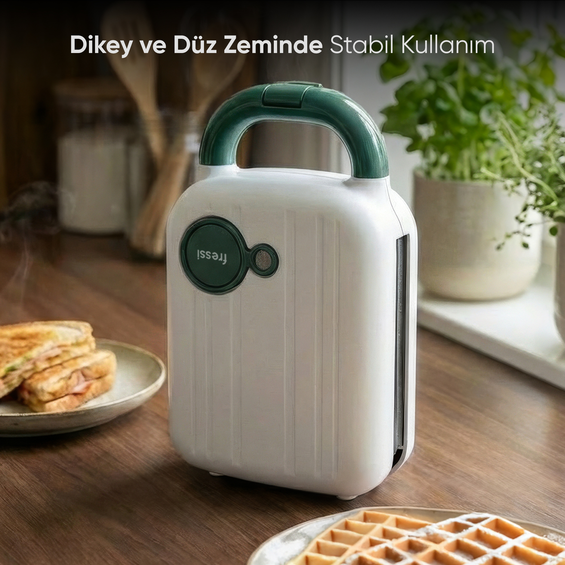 Yeşil saplı beyaz bir sandviç makinesi ahşap masada duruyor. Yanında sandviçler ve waffle'lar var.