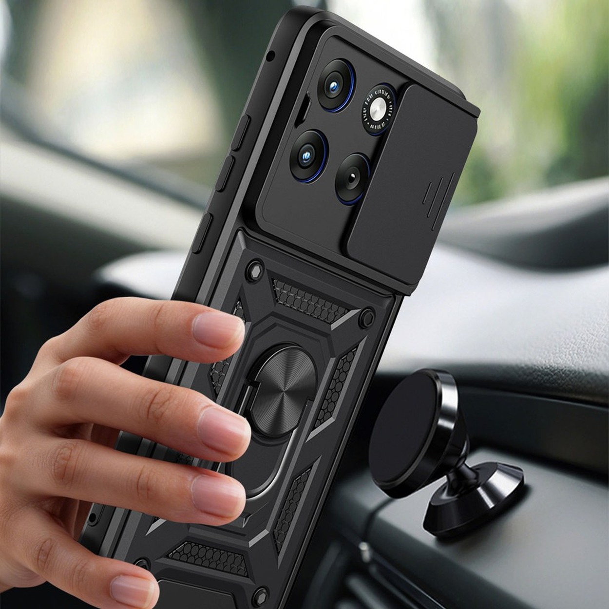Zwarte telefoonhoes met ringhouder en cameraluik, vastgehouden door hand, bij auto dashboard houder.
