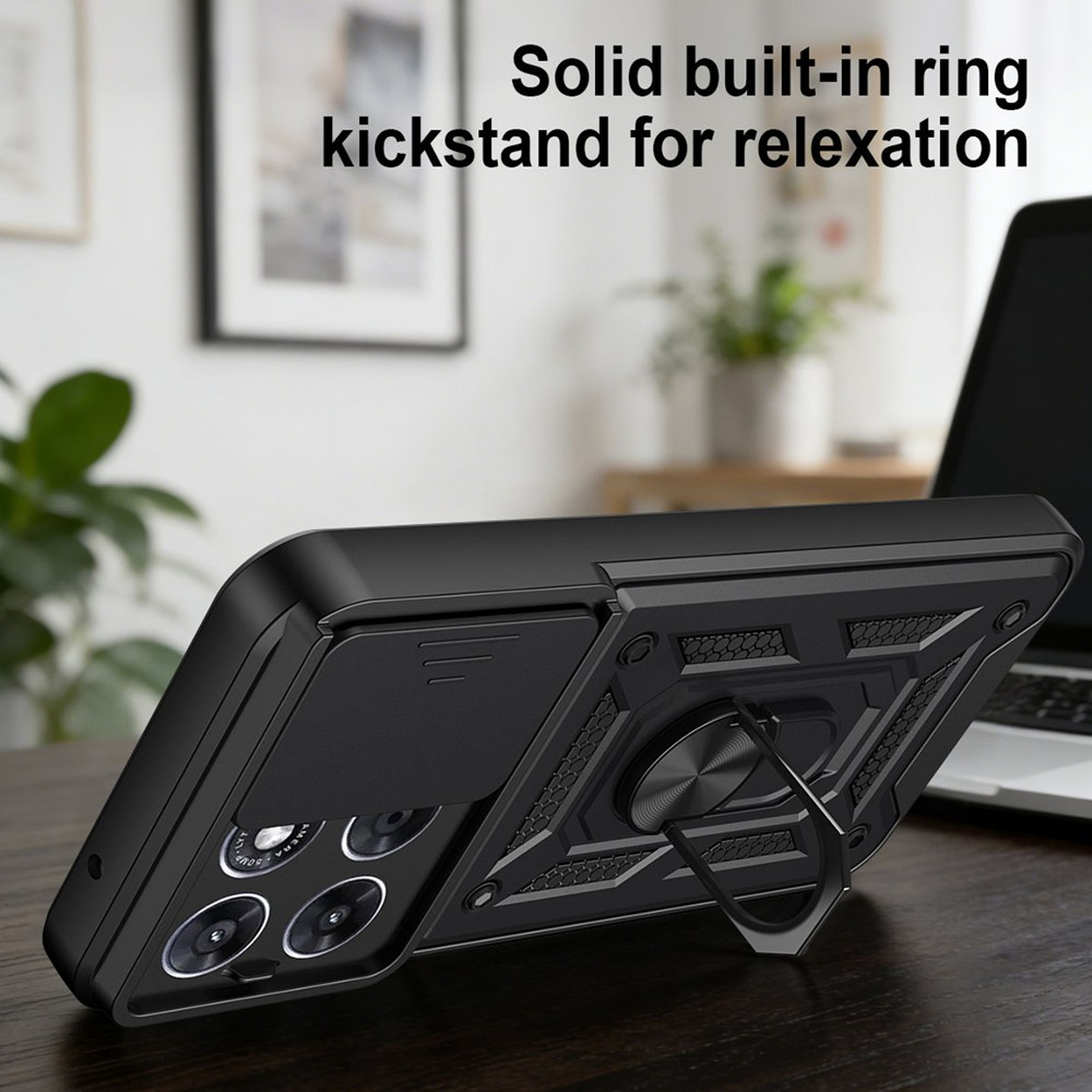 Coque de téléphone noire avec support anneau sur une table, ordinateur portable en arrière-plan.