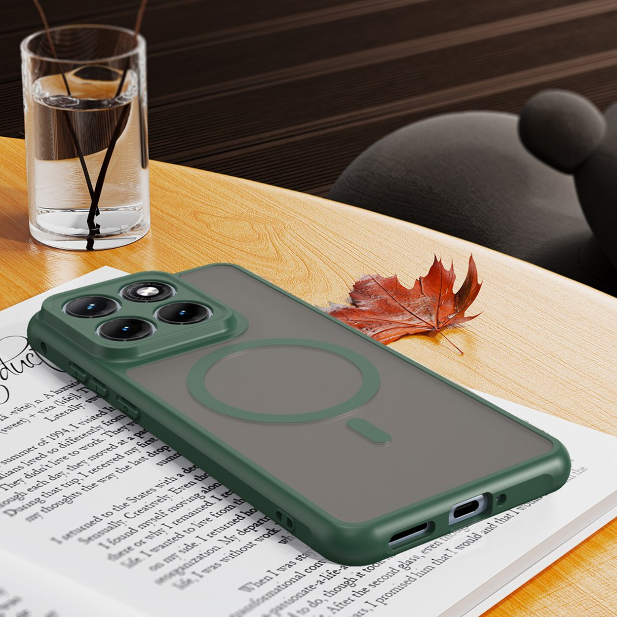 Een groene telefoonhoes met magneetring ligt op een open boek naast een glas water.