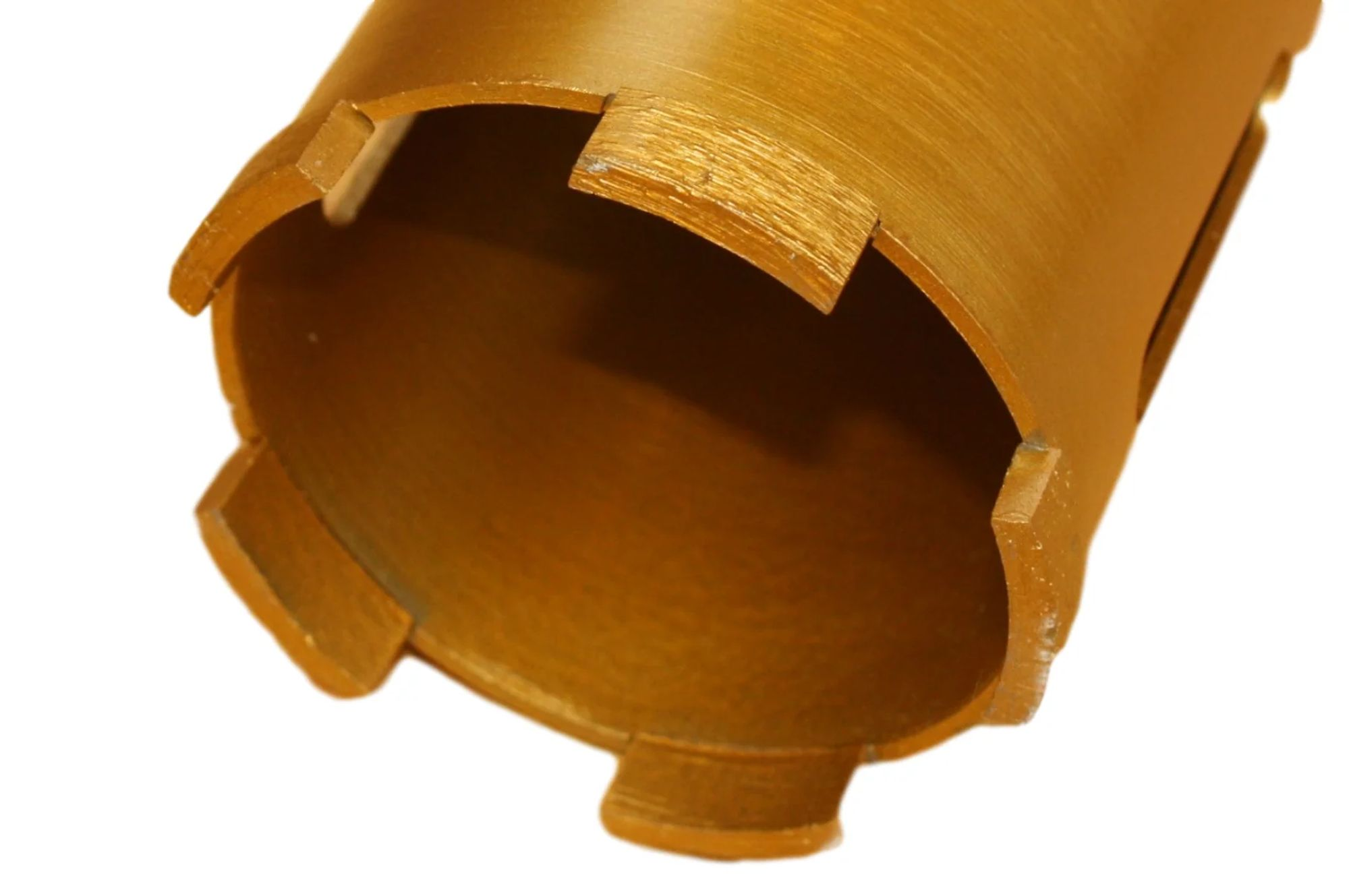 Close up of a gold colored core drill bit with visible teeth on the edge.