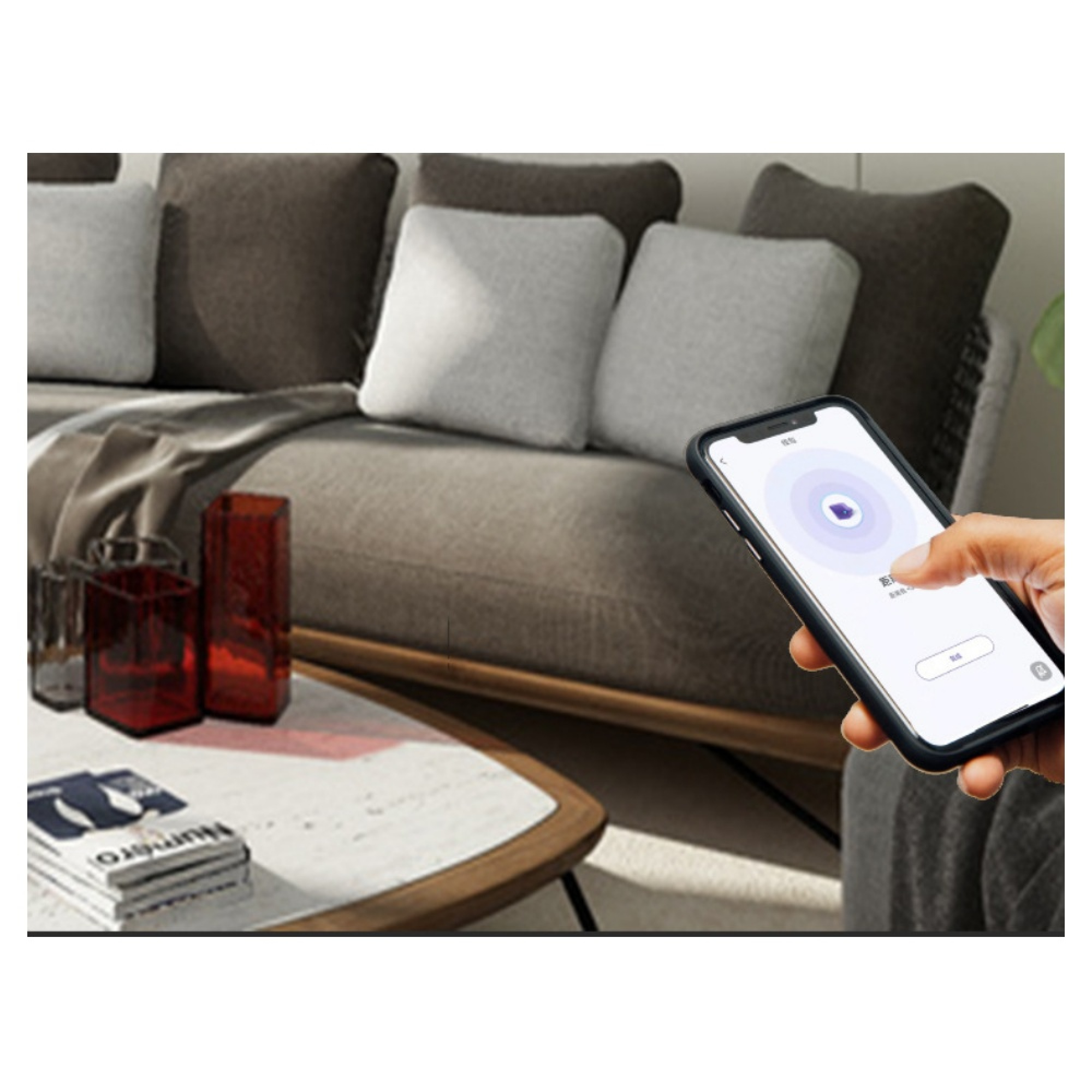 Hand hält Smartphone vor Sofa mit Kissen und roten Vasen auf Couchtisch.