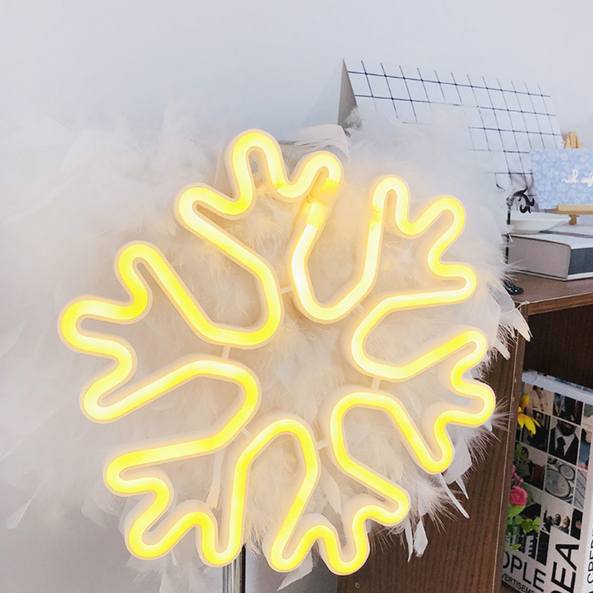 Ein gelbes Neon-Schneeflockenlicht auf weißen Federn.