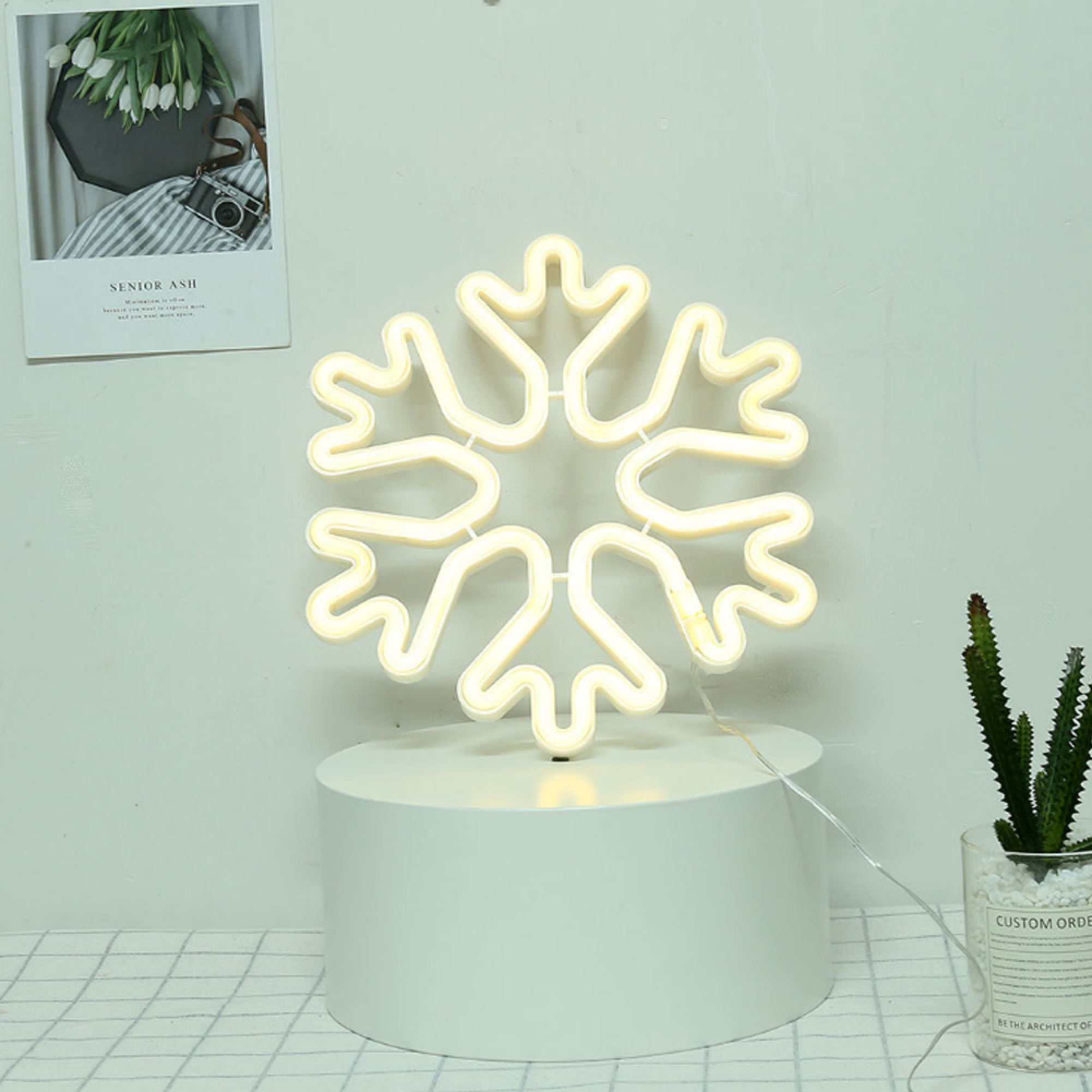 Eine leuchtende Schneeflocken-Lampe steht auf einem weißen Sockel.
