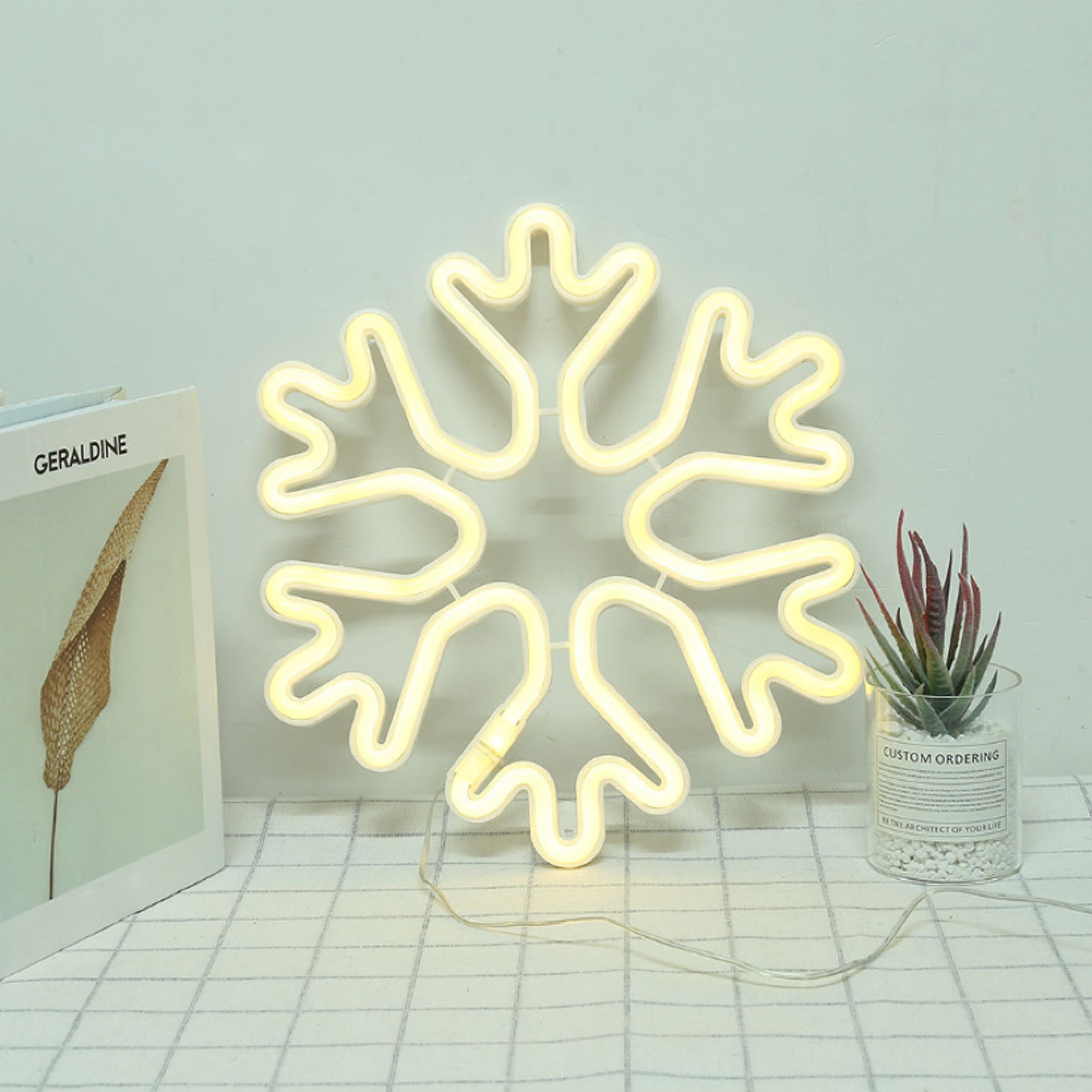 Ein weißes Neon-Schneeflockenlicht leuchtet auf einem karierten Tuch.