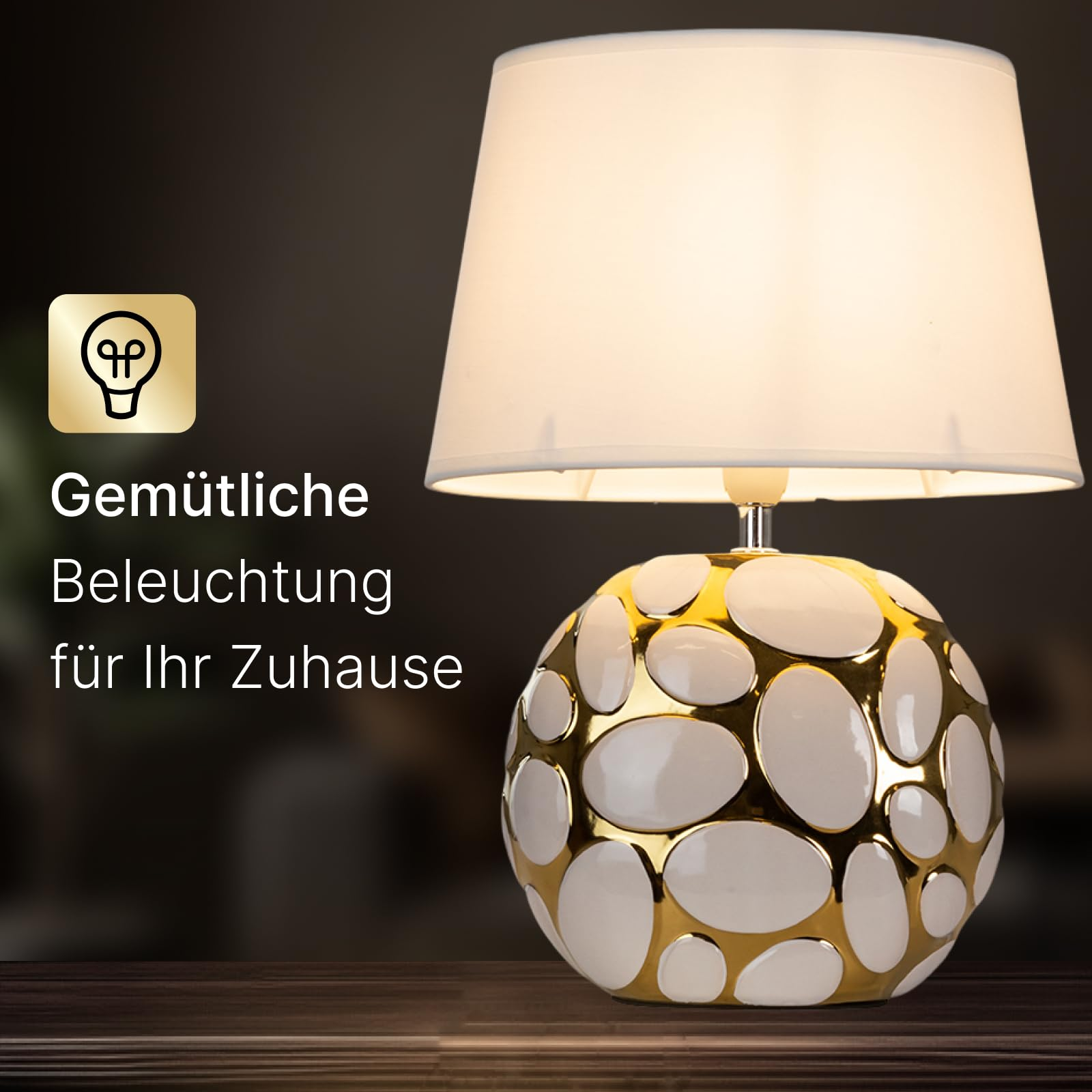 Eine Lampe mit weißem Schirm und einem goldenen, ovalen Sockel.