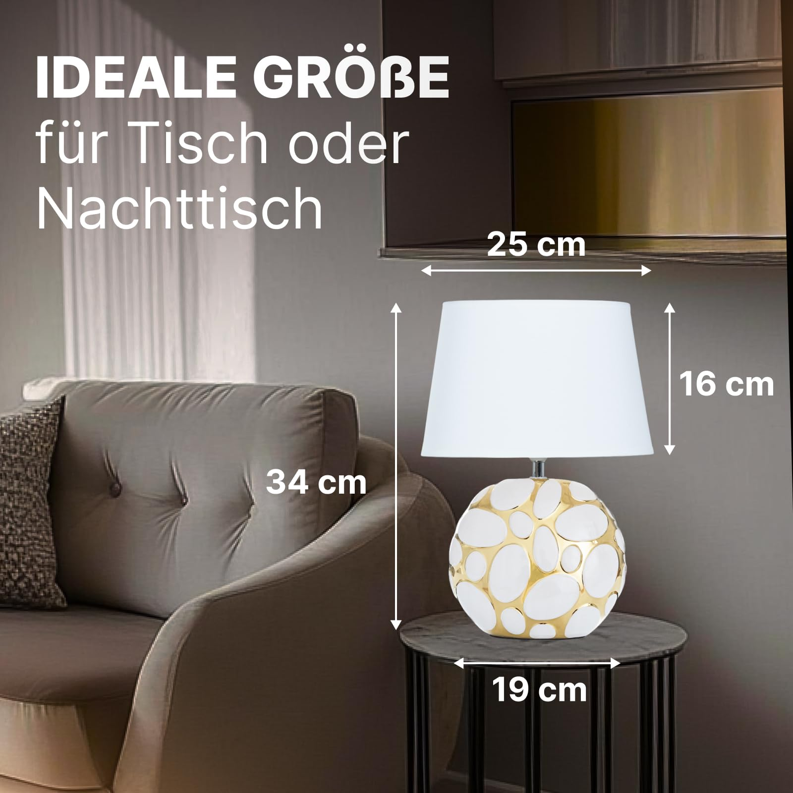 Eine Lampe mit weißem Schirm und kugelförmigem Sockel mit Goldmuster steht auf einem Tisch.
