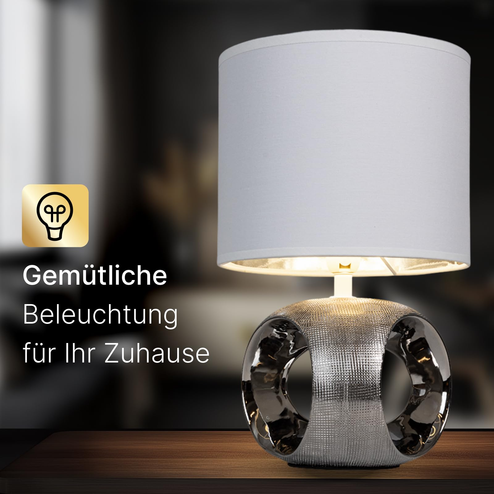 Eine silberne Lampe mit weißem Schirm steht auf einem Holztisch.
