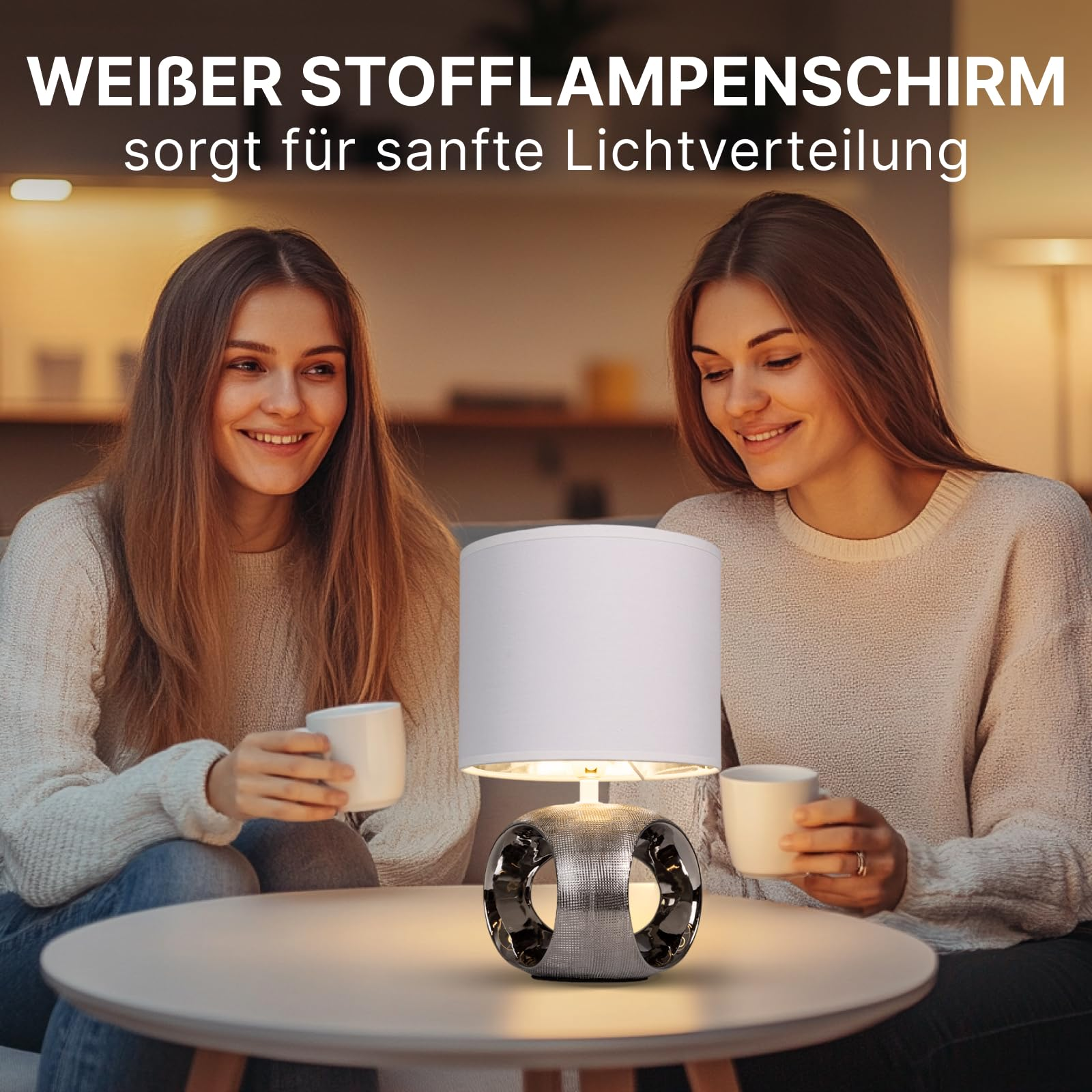 Zwei Frauen trinken Kaffee neben einer Lampe mit weißem Stoffschirm.