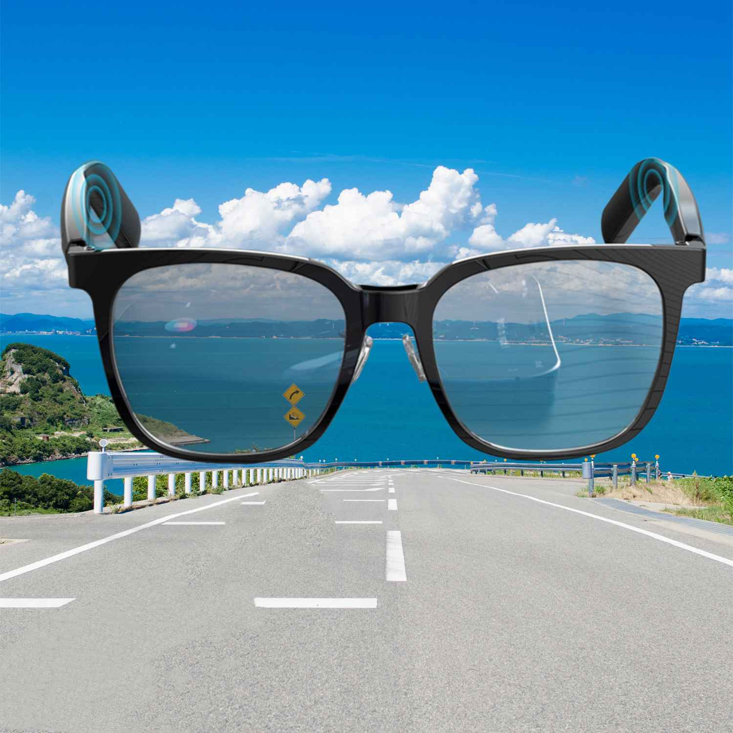 Schwarze Brille mit Lautsprechern, über einer Küstenstraße mit blauem Himmel.
