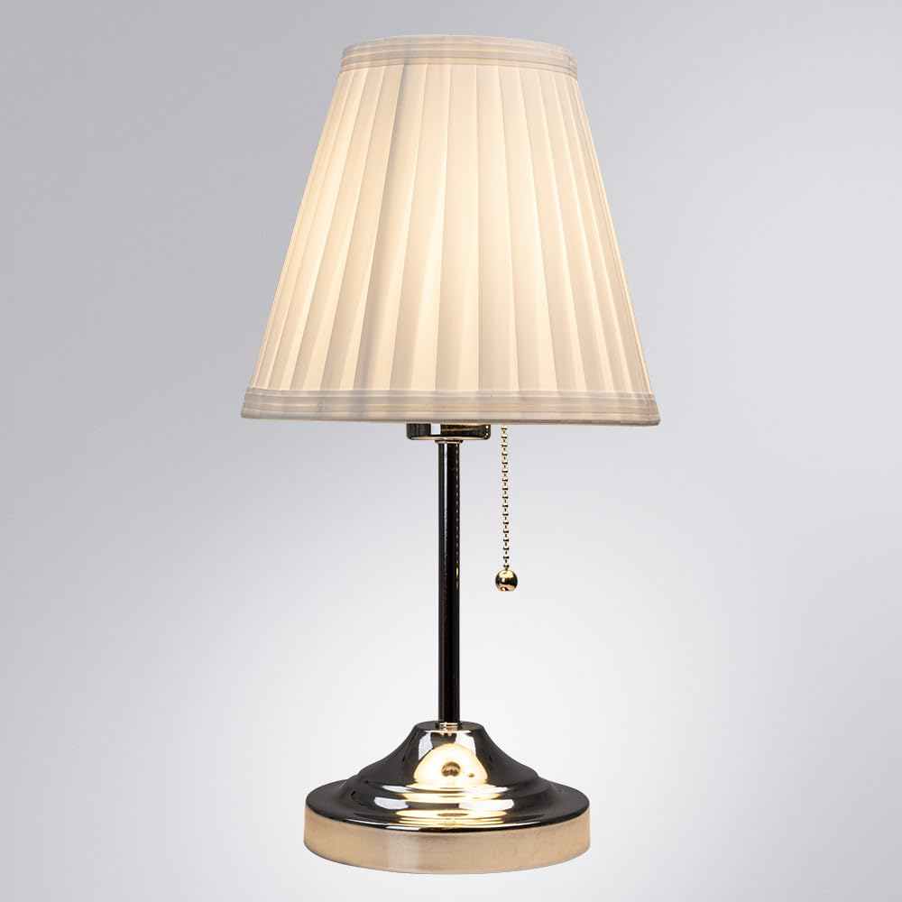 Eine klassische Tischlampe mit einem plissierten weißen Schirm und einem glänzenden Metallsockel und Stiel.