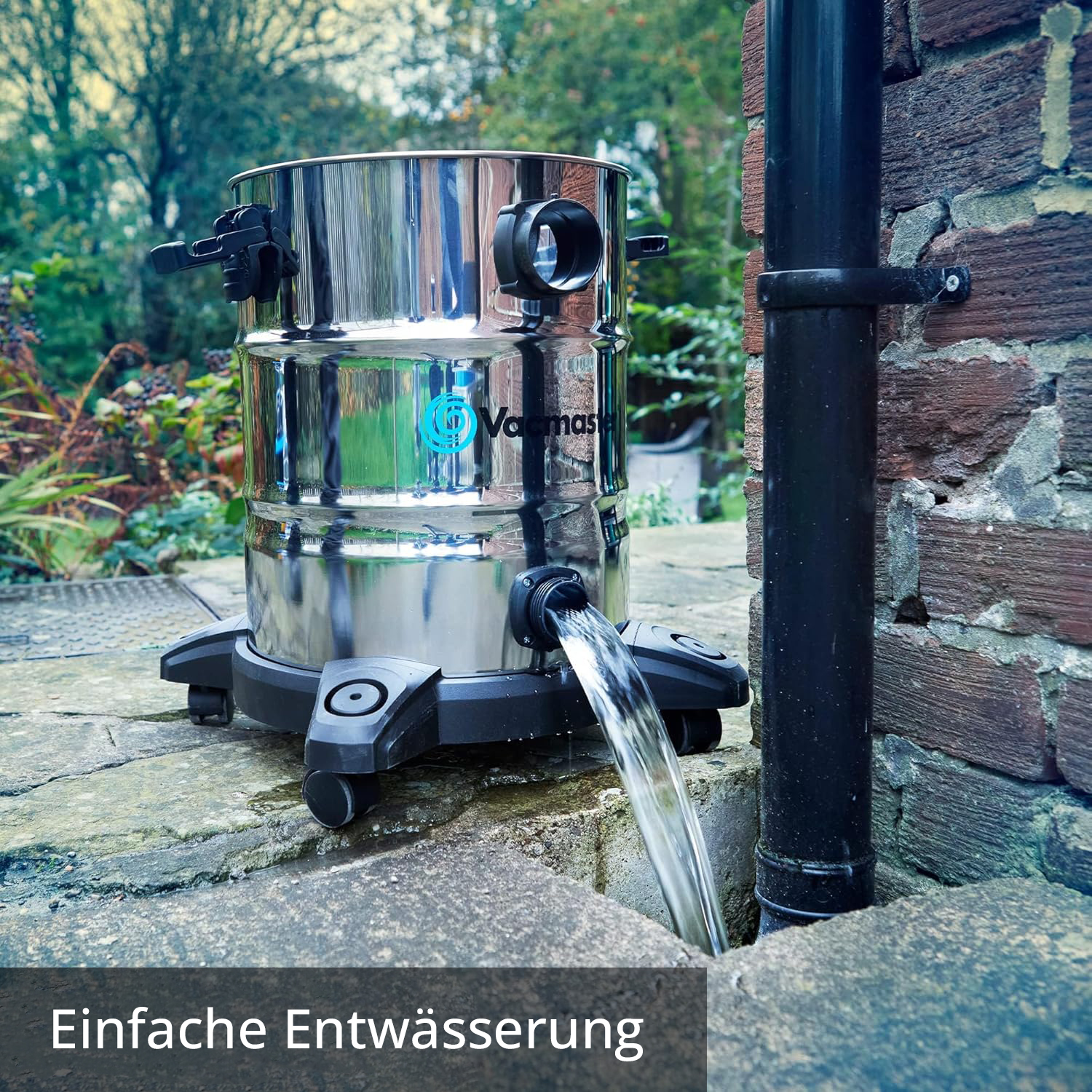 Ein silberner Vacmas Nasssauger leert Wasser auf einen Steinweg neben einer Ziegelmauer.