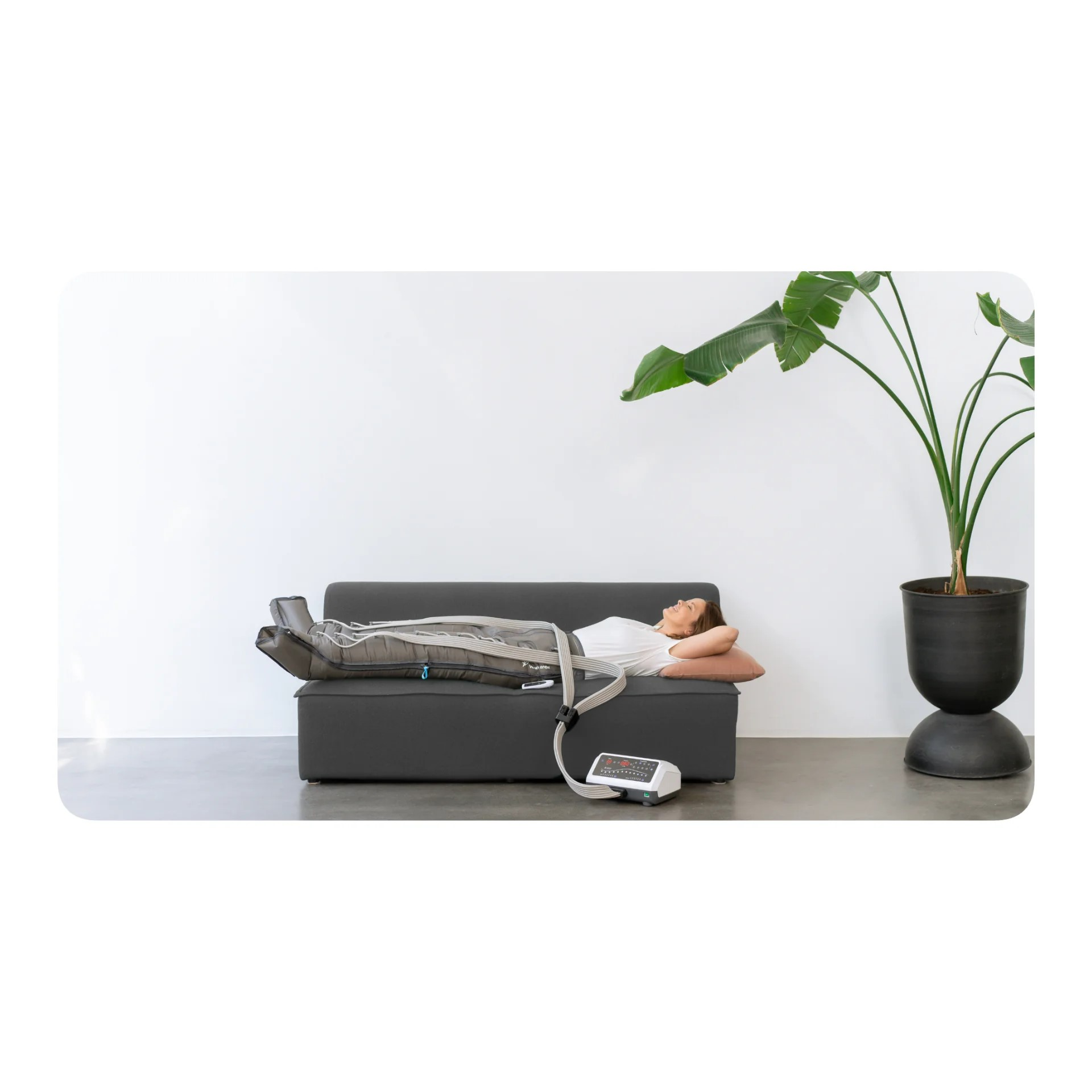 Eine Frau liegt auf einer Couch mit Kompressionsstiefeln an ihren Beinen.