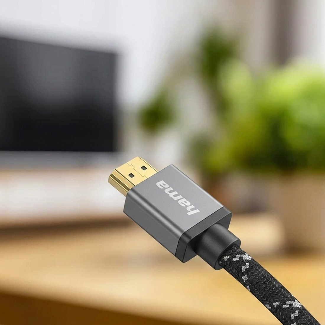 Kabel HDMI ze złotym złączem i logo Hama, na rozmytym tle.