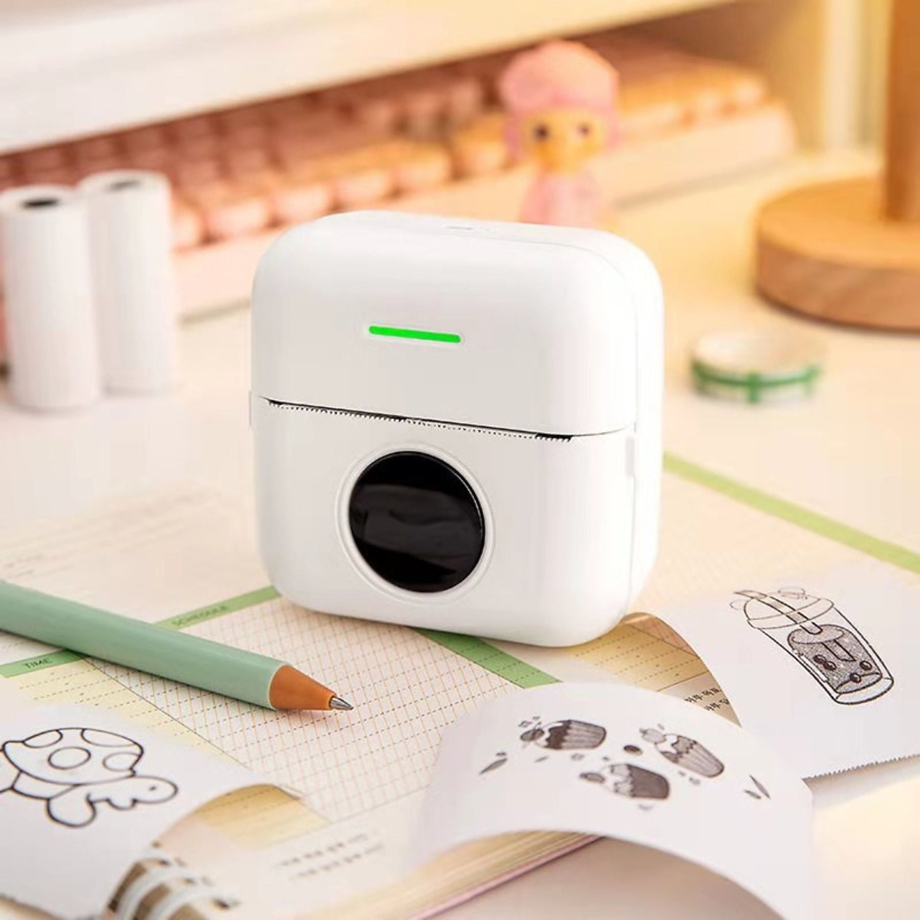 Ein weißer Mini-Drucker mit grüner LED, Stift und gedruckten Bildern auf einem Schreibtisch.