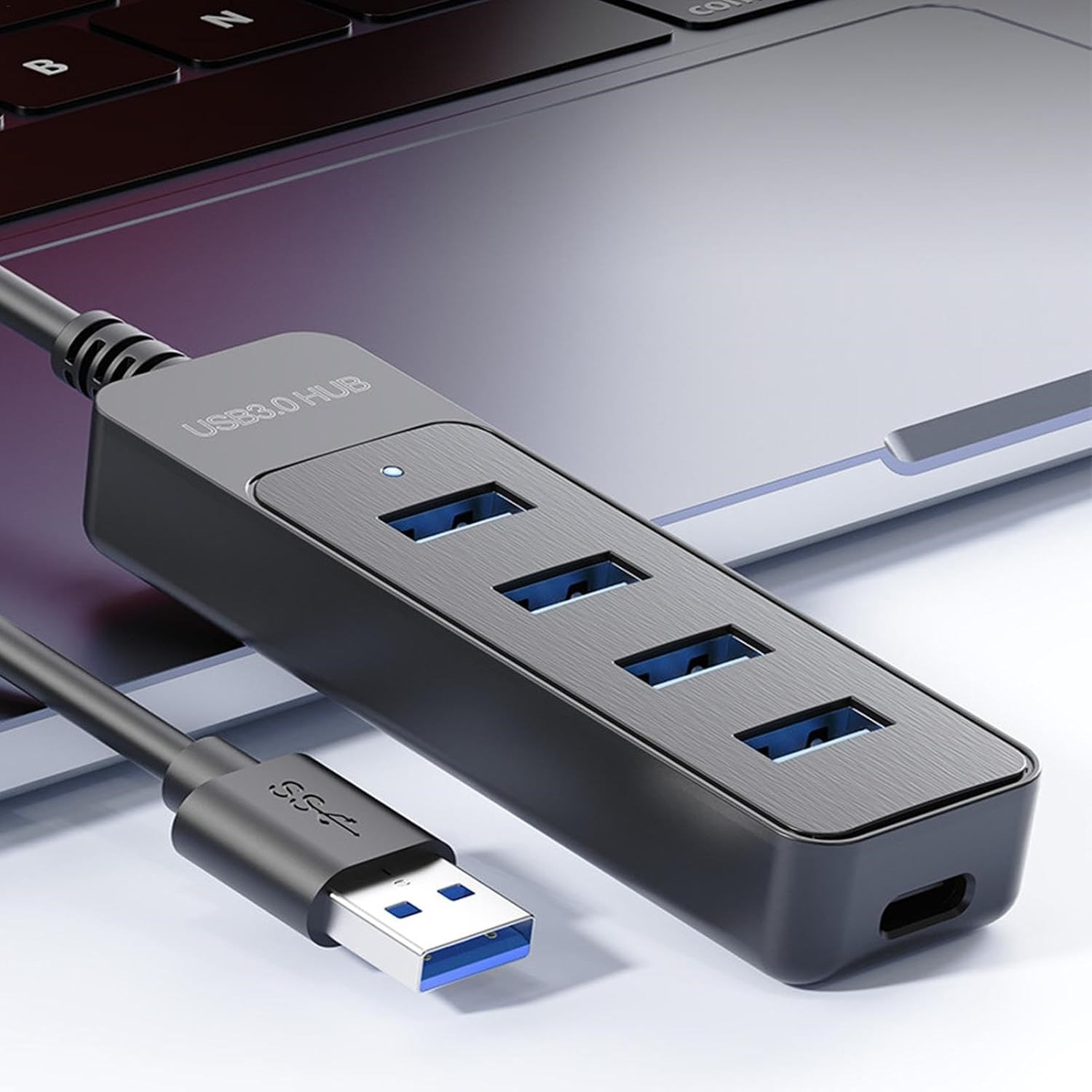 Dört mavi bağlantı noktasına sahip siyah bir USB 3.0 hub bir dizüstü bilgisayara bağlı.