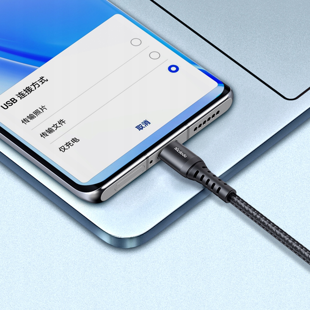 Ein Smartphone wird mit einem schwarzen Kabel verbunden, das an einen Laptop angeschlossen ist.