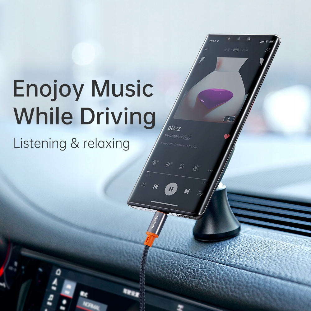 Uno smartphone riproduce musica in un'auto, collegato da un cavo di ricarica.