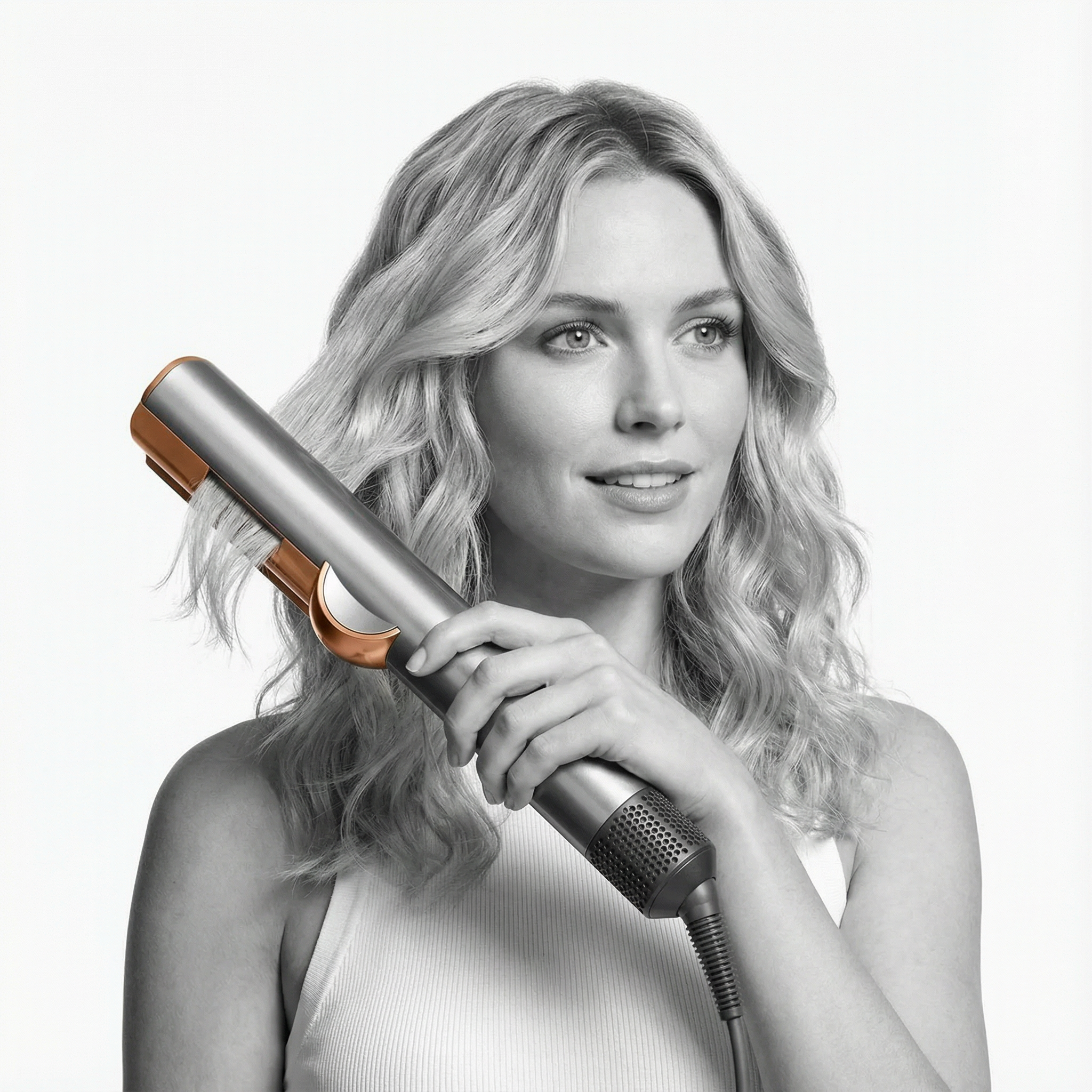 Una mujer con cabello rubio usa una herramienta plateada y de cobre para peinar.