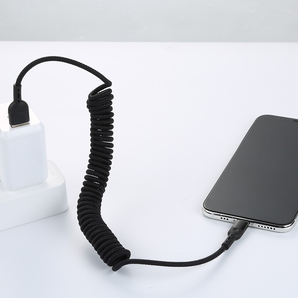 Siyah spiral kablo, beyaz bir arj letini bir akıllı telefona bağlar.