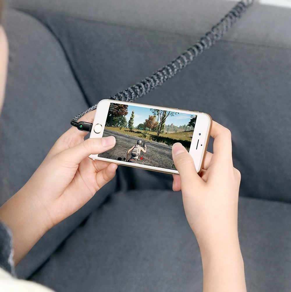 Şarj kablosuna bağlı bir akıllı telefonda video oyunu oynayan kişi.