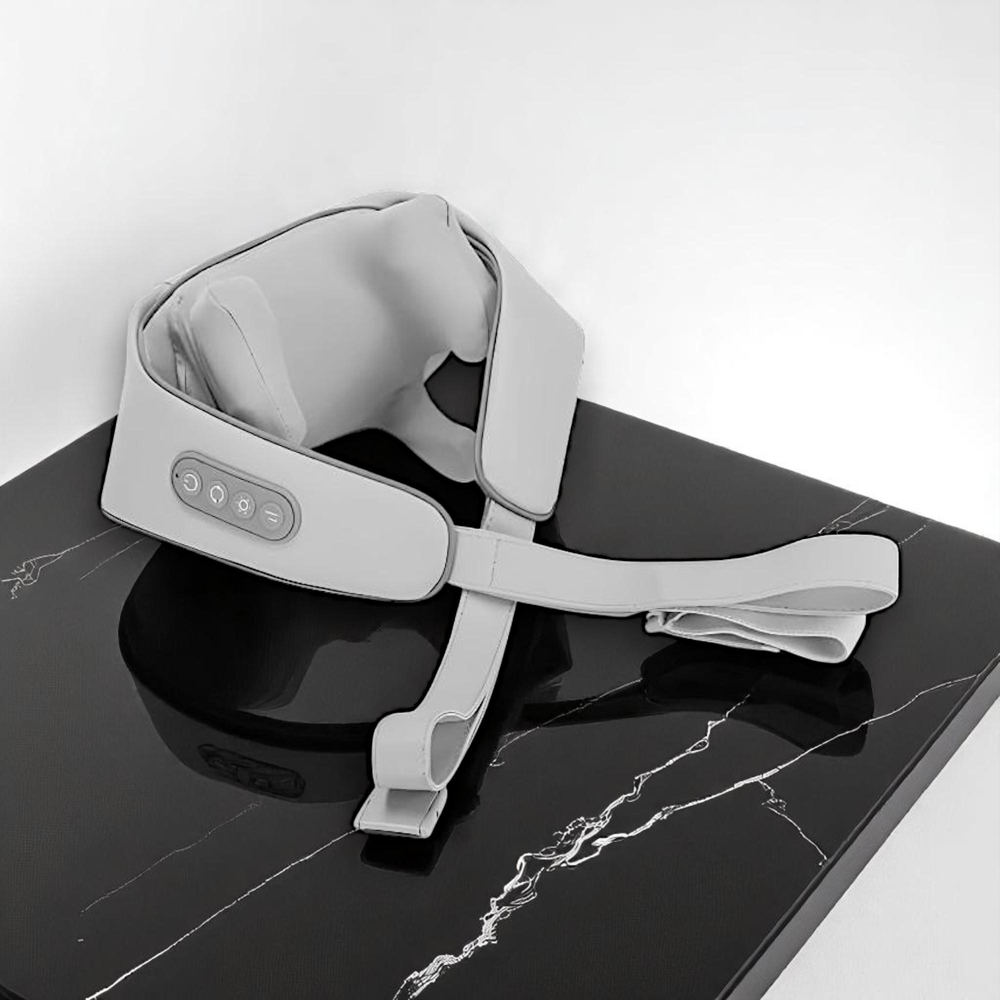 Masajeador de cuello gris con controles sobre una mesa de mármol negro.