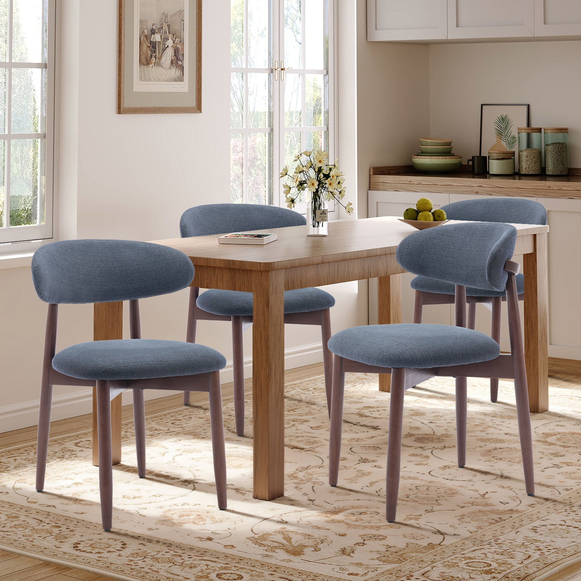 Ein Holztisch mit vier blauen Stühlen in einem Esszimmer mit Fenstern und einem Teppich.