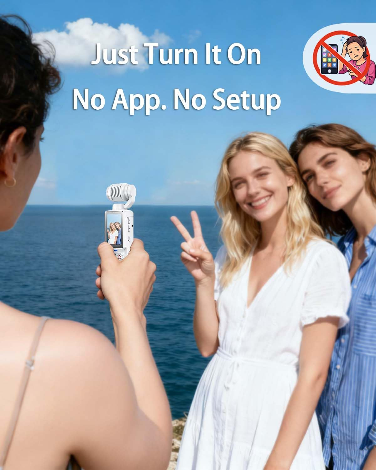 Zwei Frauen posieren am Meer, eine hält eine Kamera. Blauer Himmel.