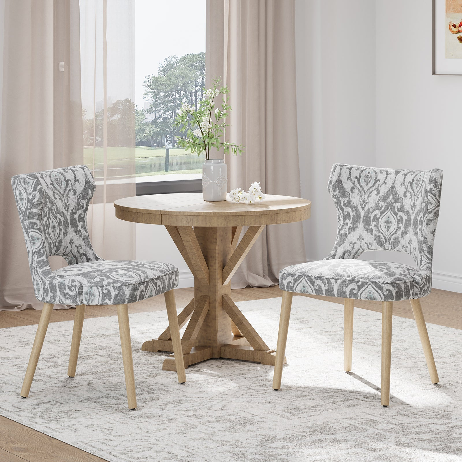 Zwei gemusterte Stühle stehen neben einem Holztisch mit Vase und Blumen.