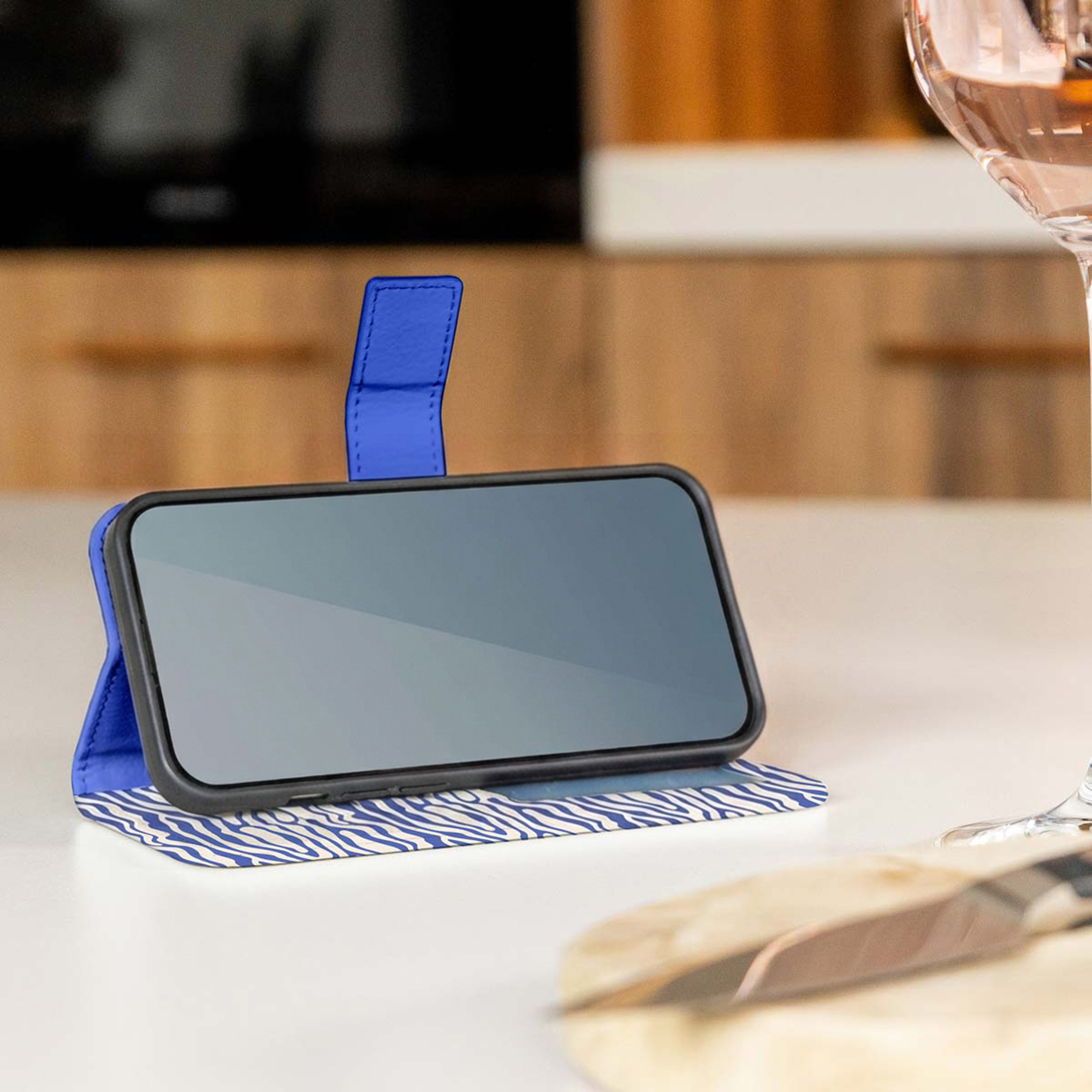 Een blauwe telefoonhoes met zebraprintbasis staat op tafel.
