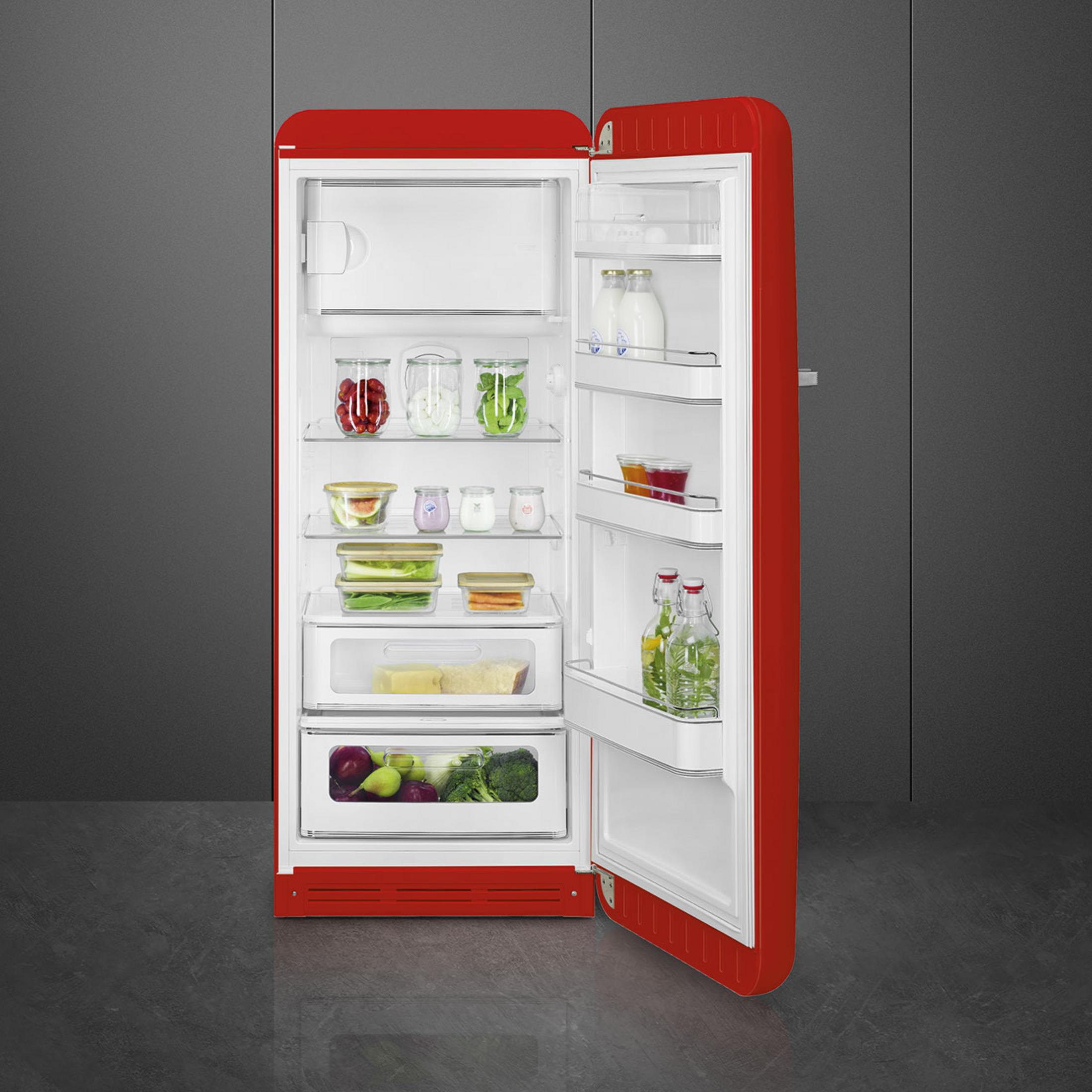 Un frigorifero rosso aperto contiene frutta, verdura, latte e bottiglie.