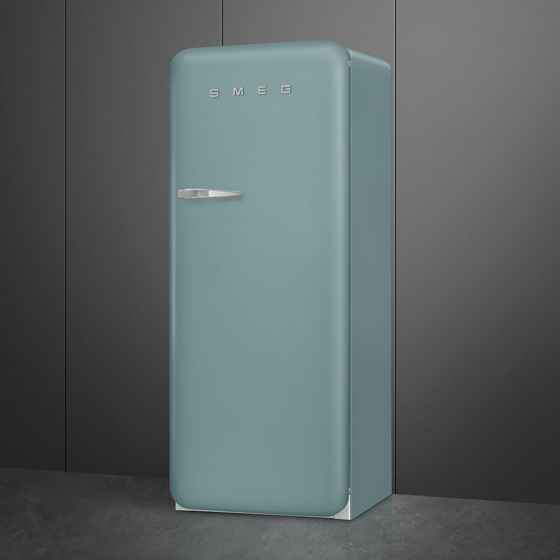 Un semplice frigorifero Smeg color verde acqua si erge contro un muro scuro.