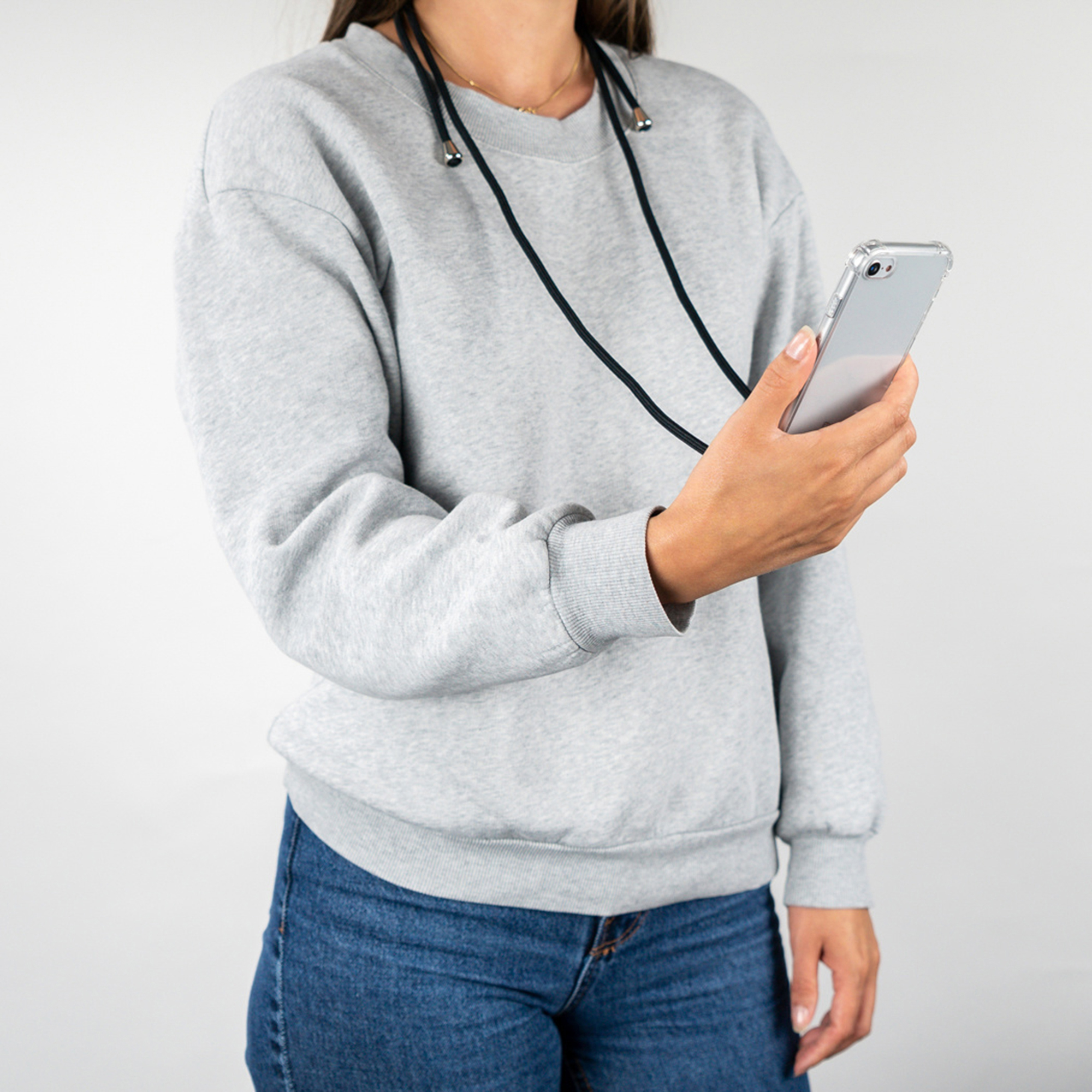 Una persona con felpa grigia e jeans blu tiene uno smartphone.