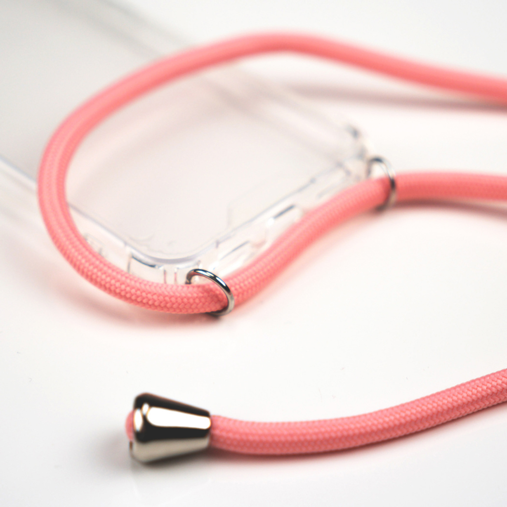 Een roze koordlanyard met zilveren beslag rust op een doorzichtige telefoonhoes.