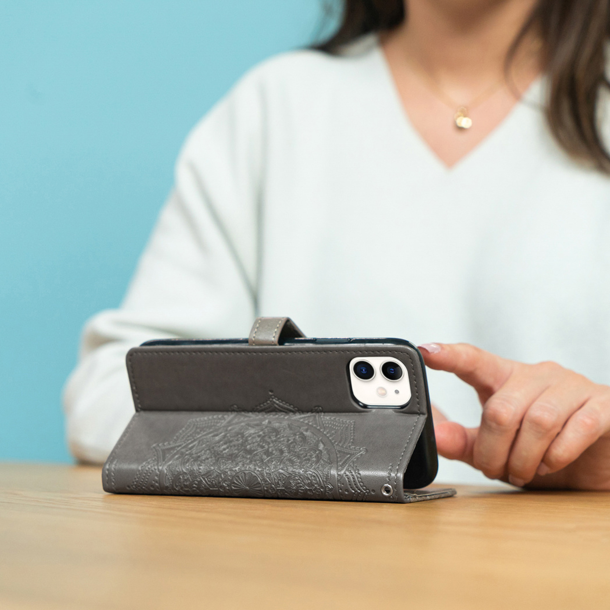 Custodia grigia per telefono con motivo mandala, su un tavolo.