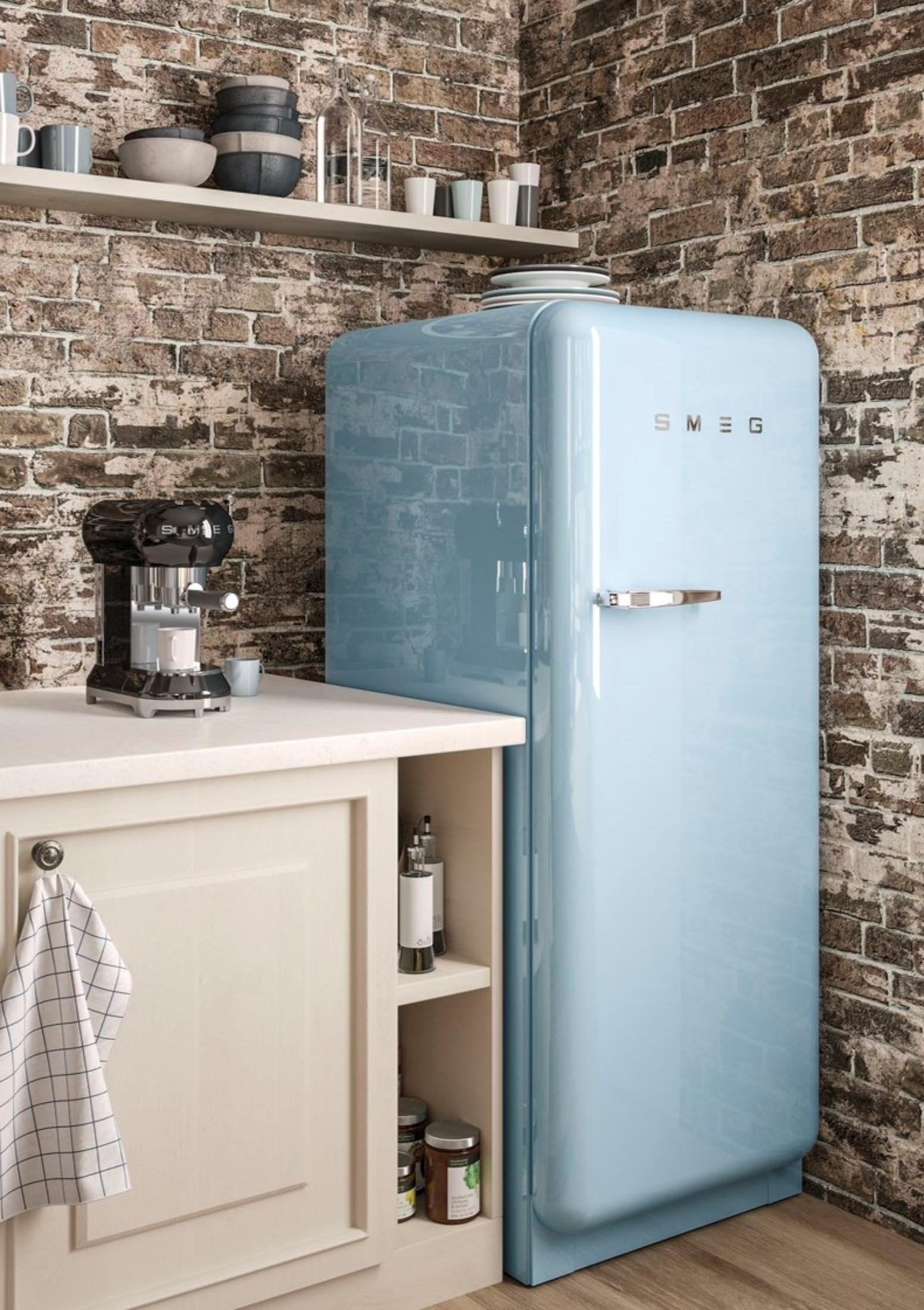 Un frigorífico Smeg retro azul claro en una cocina con pared de ladrillos y cafetera.