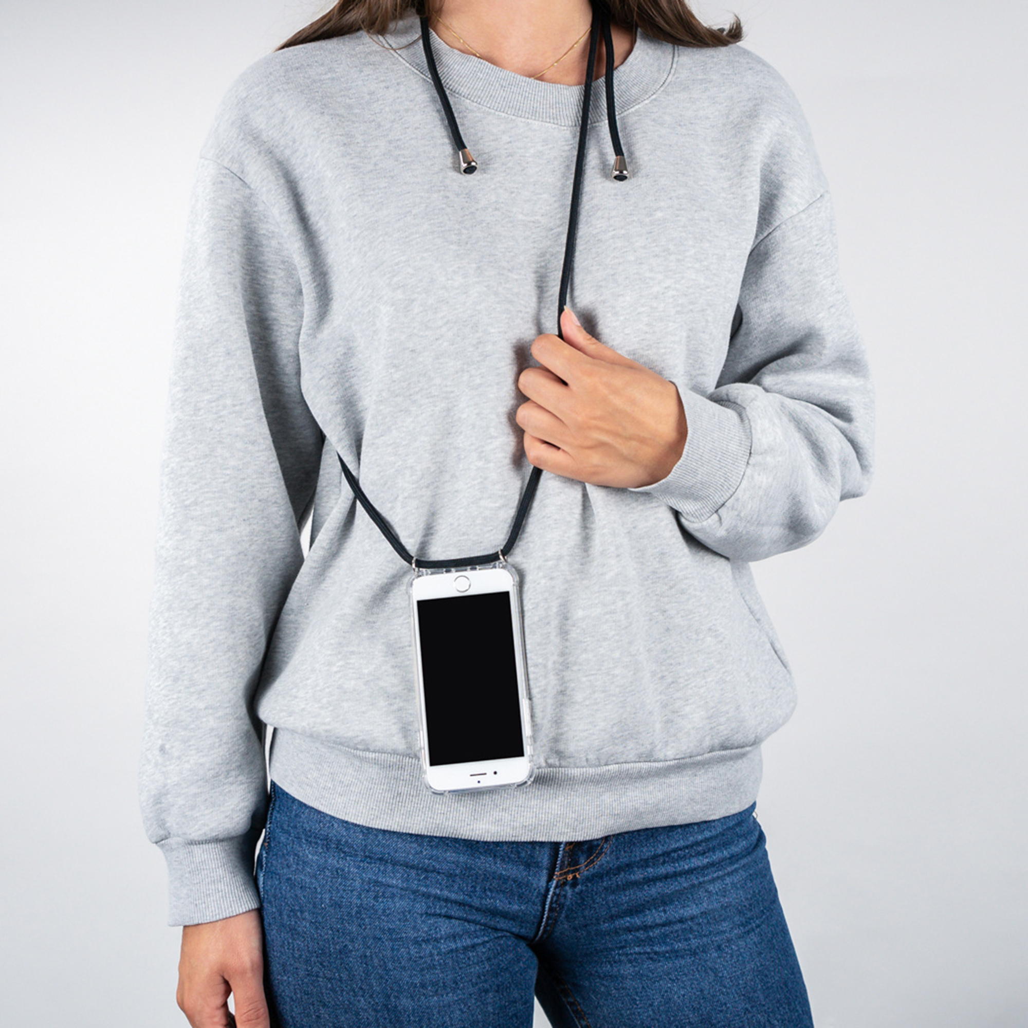 Eine Person trägt einen grauen Pullover und blaue Jeans mit einem Smartphone, das an einer Kordel hängt.