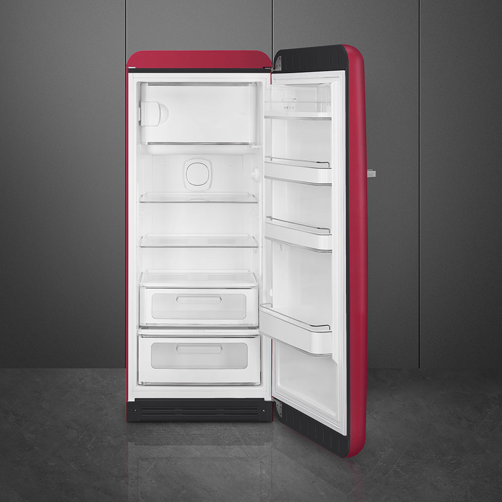 Un frigorifero rosso con porta aperta, vuoto con ripiani e cassetti.