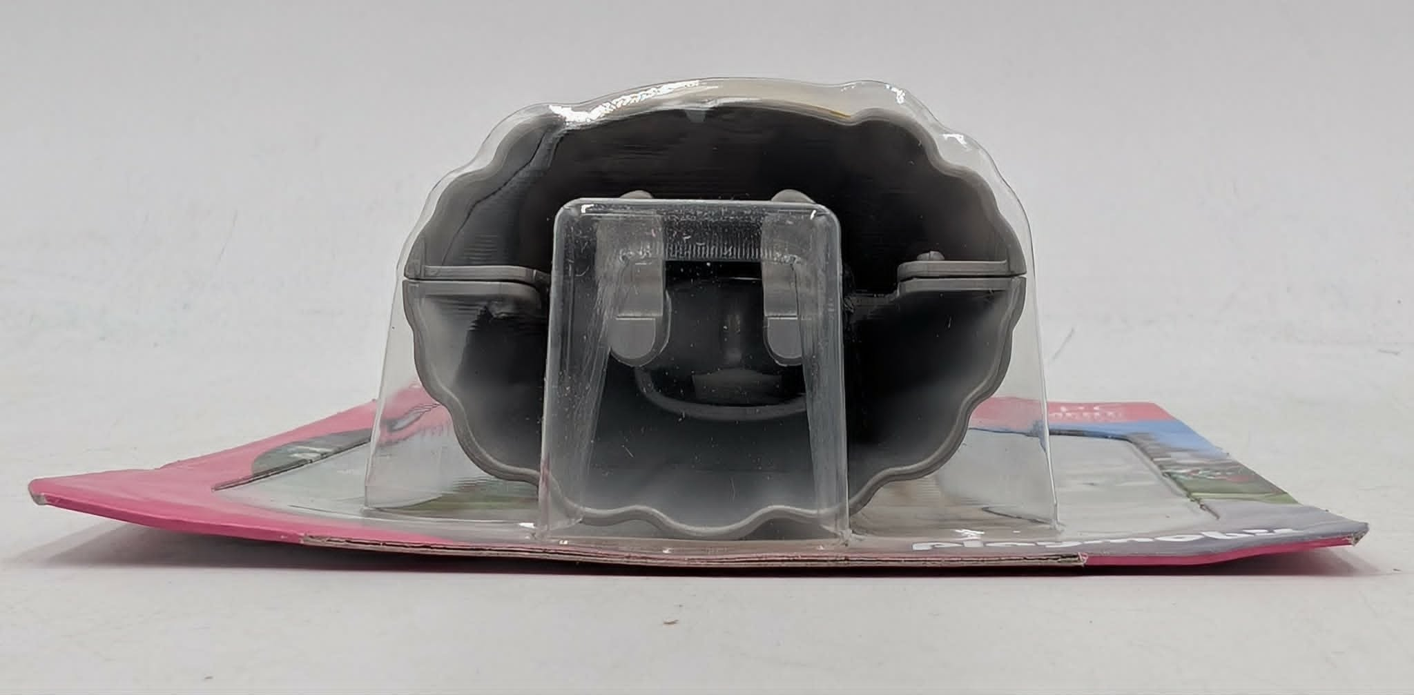 Ein graues Objekt in einer durchsichtigen Verpackung mit rosa Hintergrund.