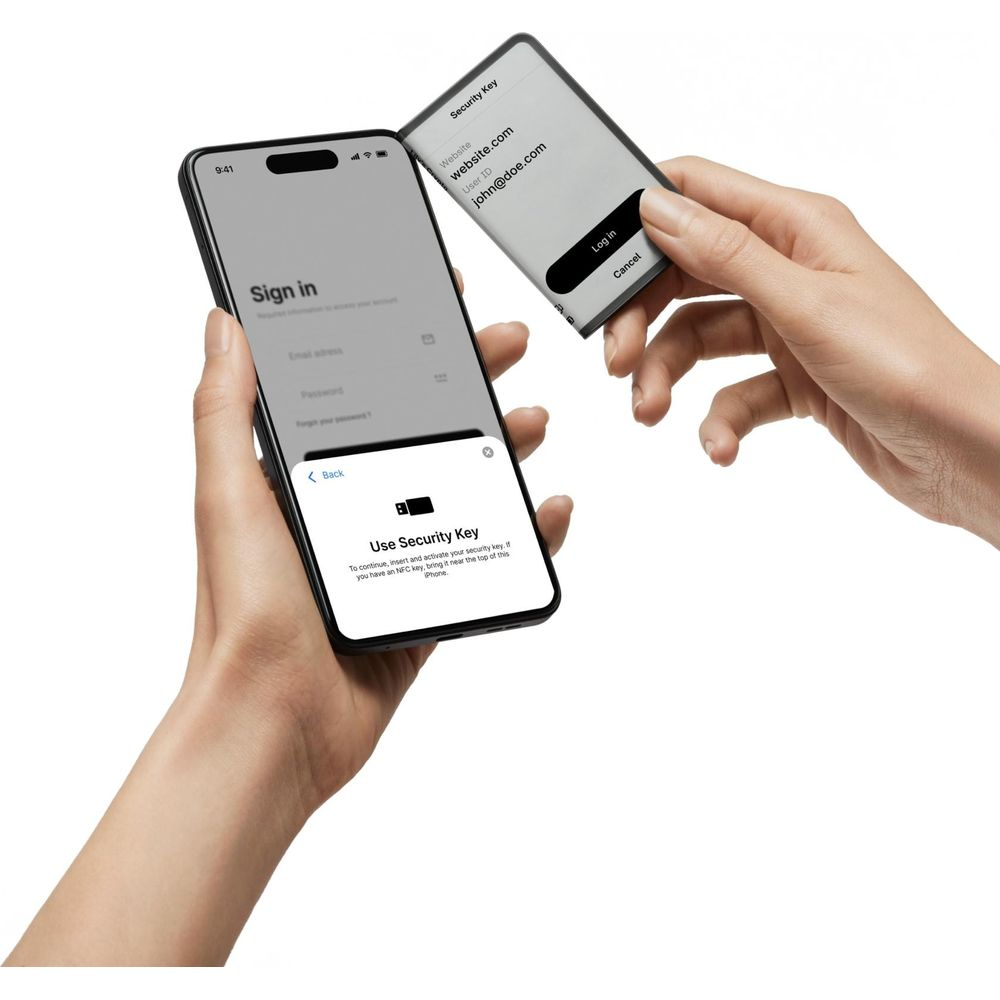 Une main tient un iPhone avec un écran de connexion, une autre main tient une clé de sécurité.