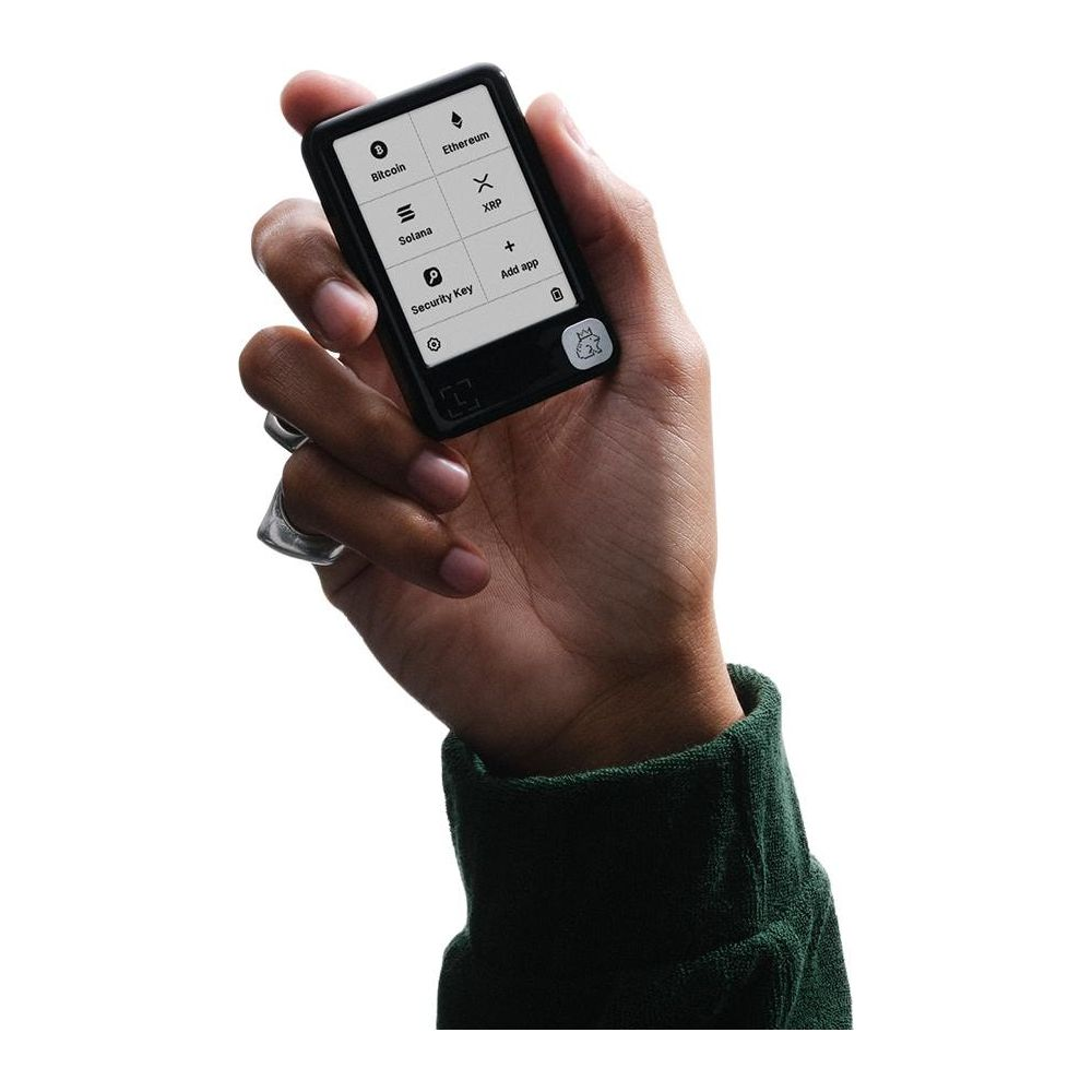 Une main tient un portefeuille matériel crypto noir affichant Bitcoin, Ethereum, Solana, XRP, Ajouter une app.