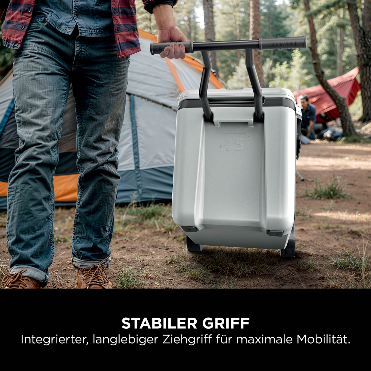 Uomo tira un frigo grigio con manici e ruote in una foresta. Tende sullo sfondo.
